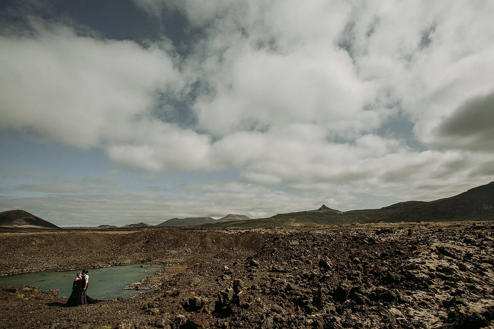 Alternative Iceland elopement couple wearing black wedding dress and purple hair — couple portraits at black sand beach