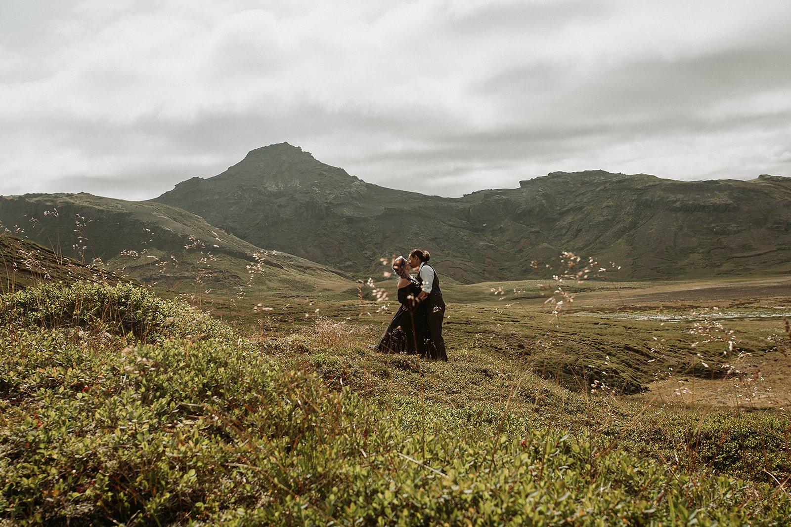 Alternative Iceland elopement couple wearing black wedding dress and purple hair — couple portraits at black sand beach