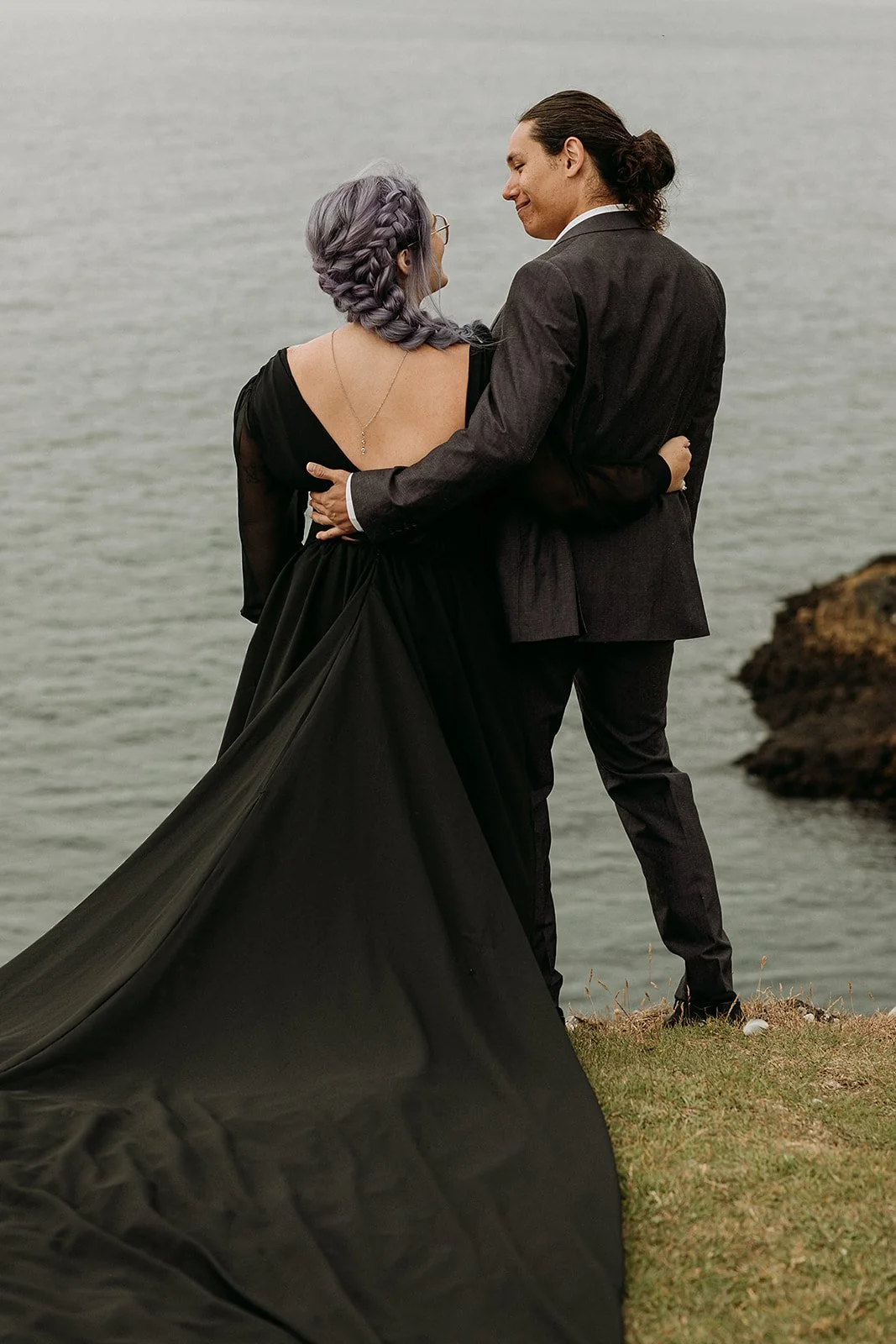 Alternative Iceland elopement couple wearing black wedding dress and purple hair — couple portraits at black sand beach