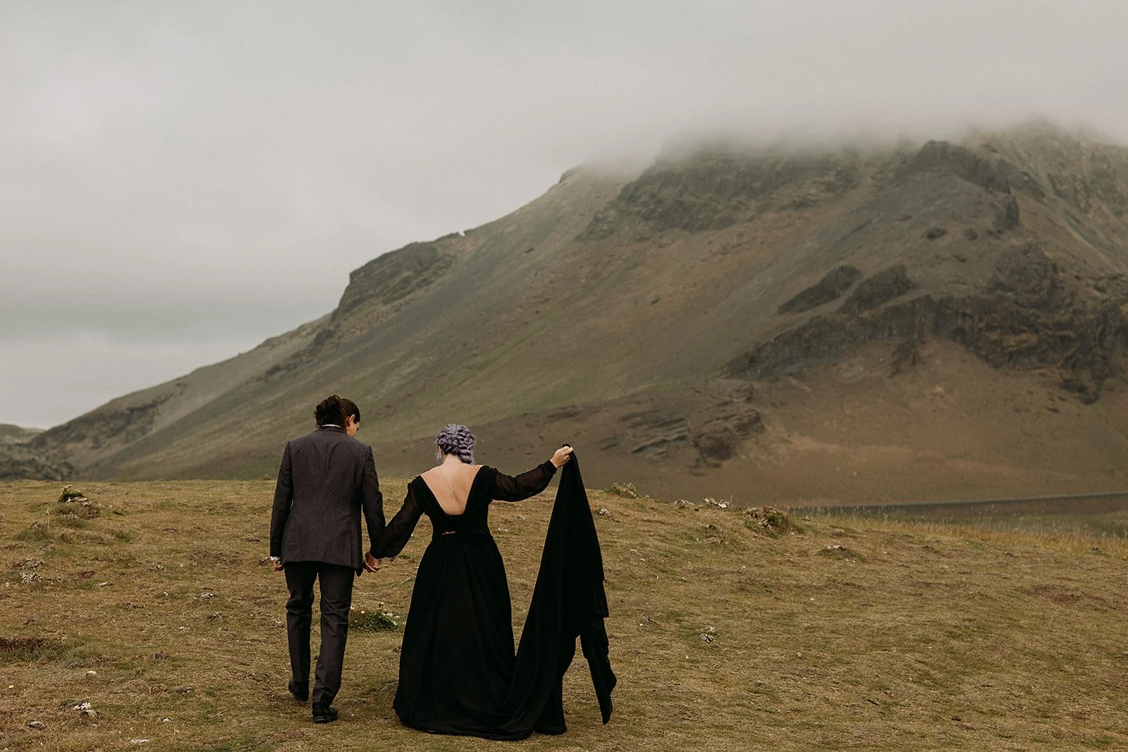 Alternative Iceland elopement couple wearing black wedding dress and purple hair — couple portraits at mountains