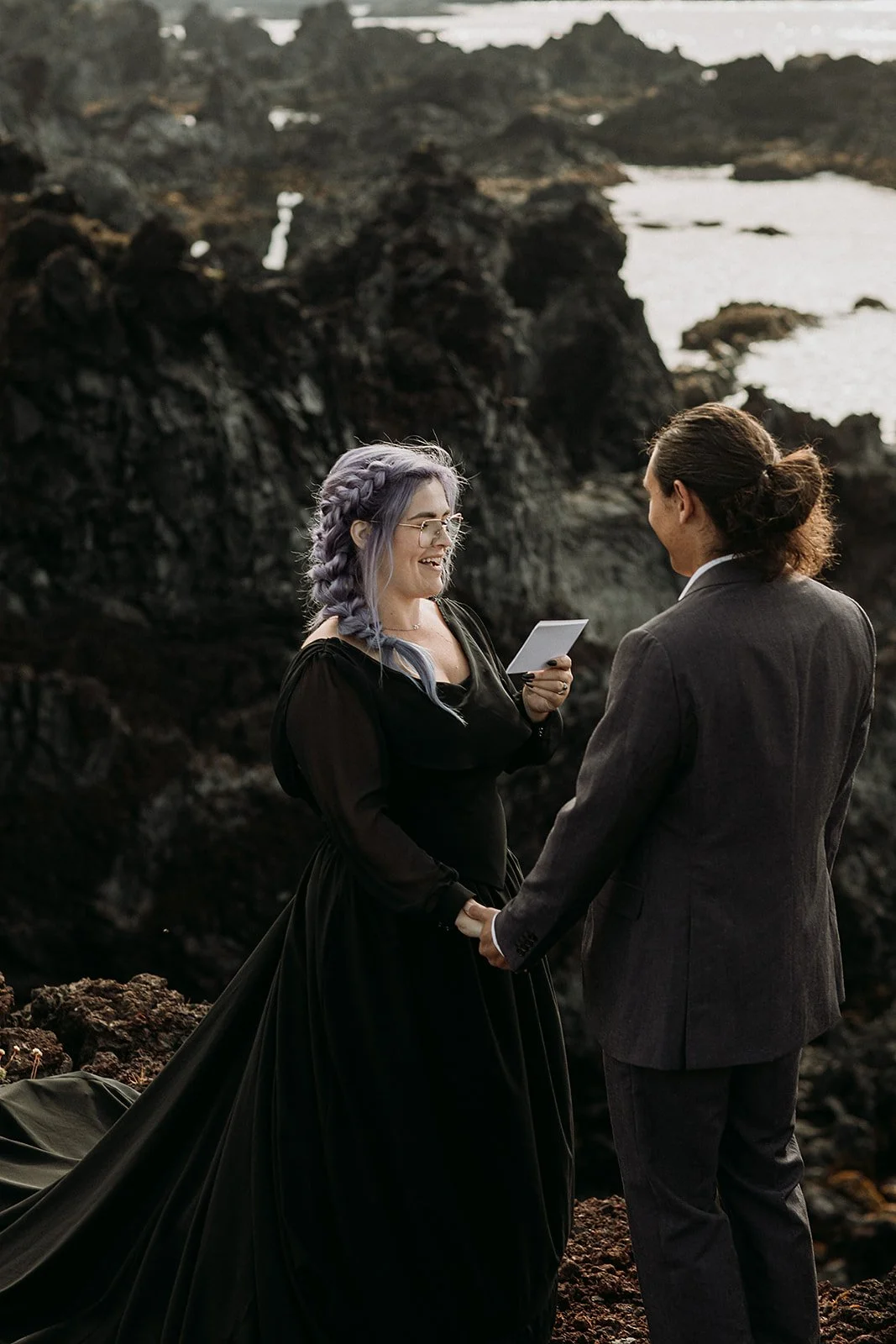 Alternative Iceland elopement couple wearing black wedding dress and purple hair — couple saying vows wedding ceremony