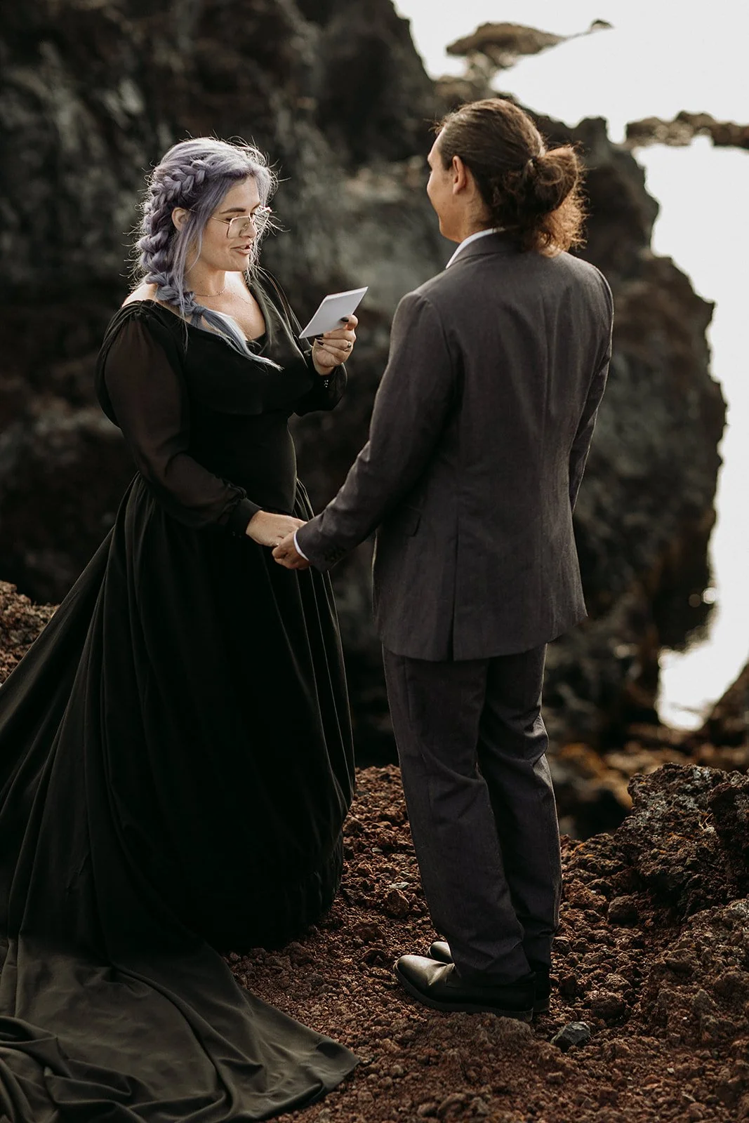 Alternative Iceland elopement couple wearing black wedding dress and purple hair — couple saying vows wedding ceremony