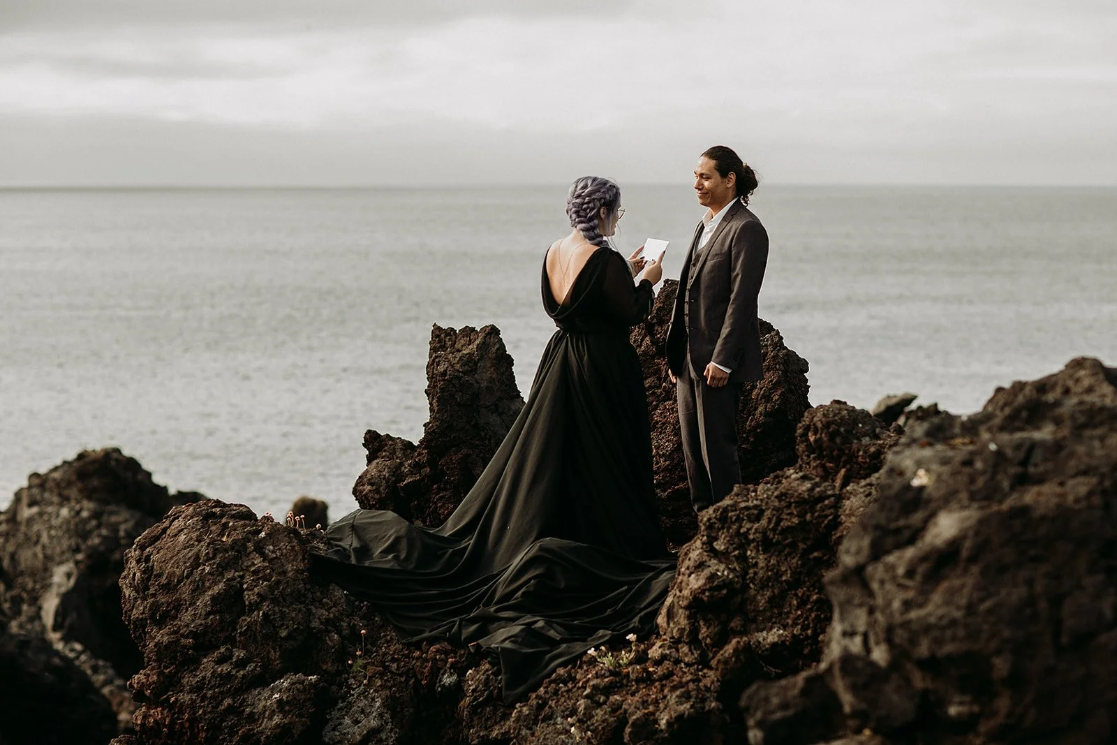Alternative Iceland elopement couple wearing black wedding dress and purple hair — couple saying vows wedding ceremony