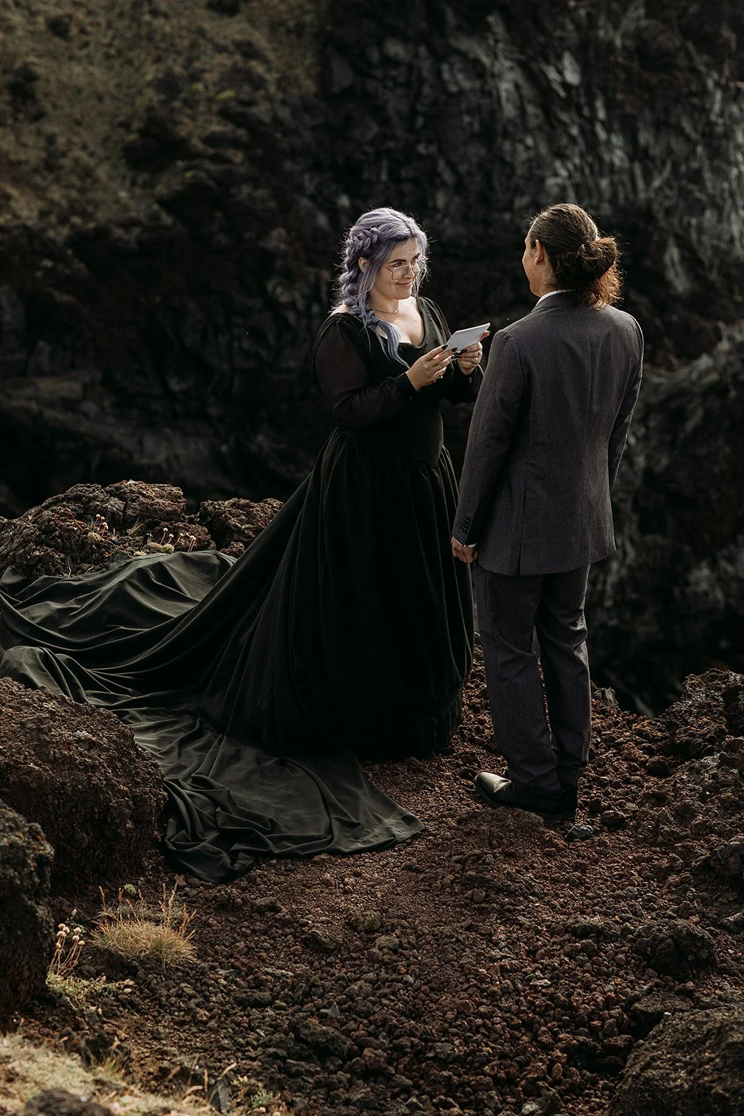 Alternative Iceland elopement couple wearing black wedding dress and purple hair — couple saying vows wedding ceremony
