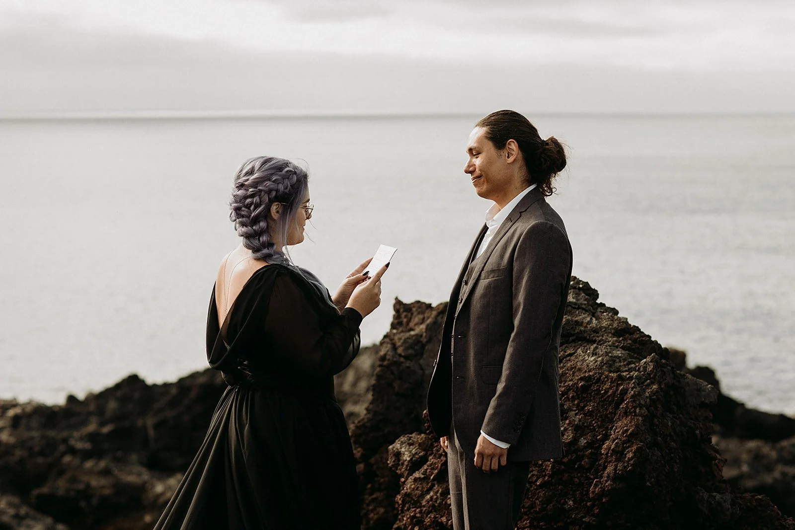 Alternative Iceland elopement couple wearing black wedding dress and purple hair — couple saying vows wedding ceremony
