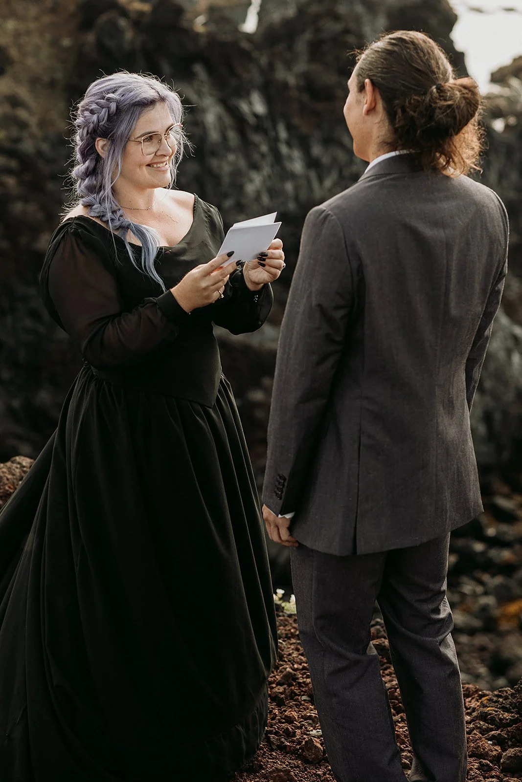 Alternative Iceland elopement couple wearing black wedding dress and purple hair — couple saying vows wedding ceremony