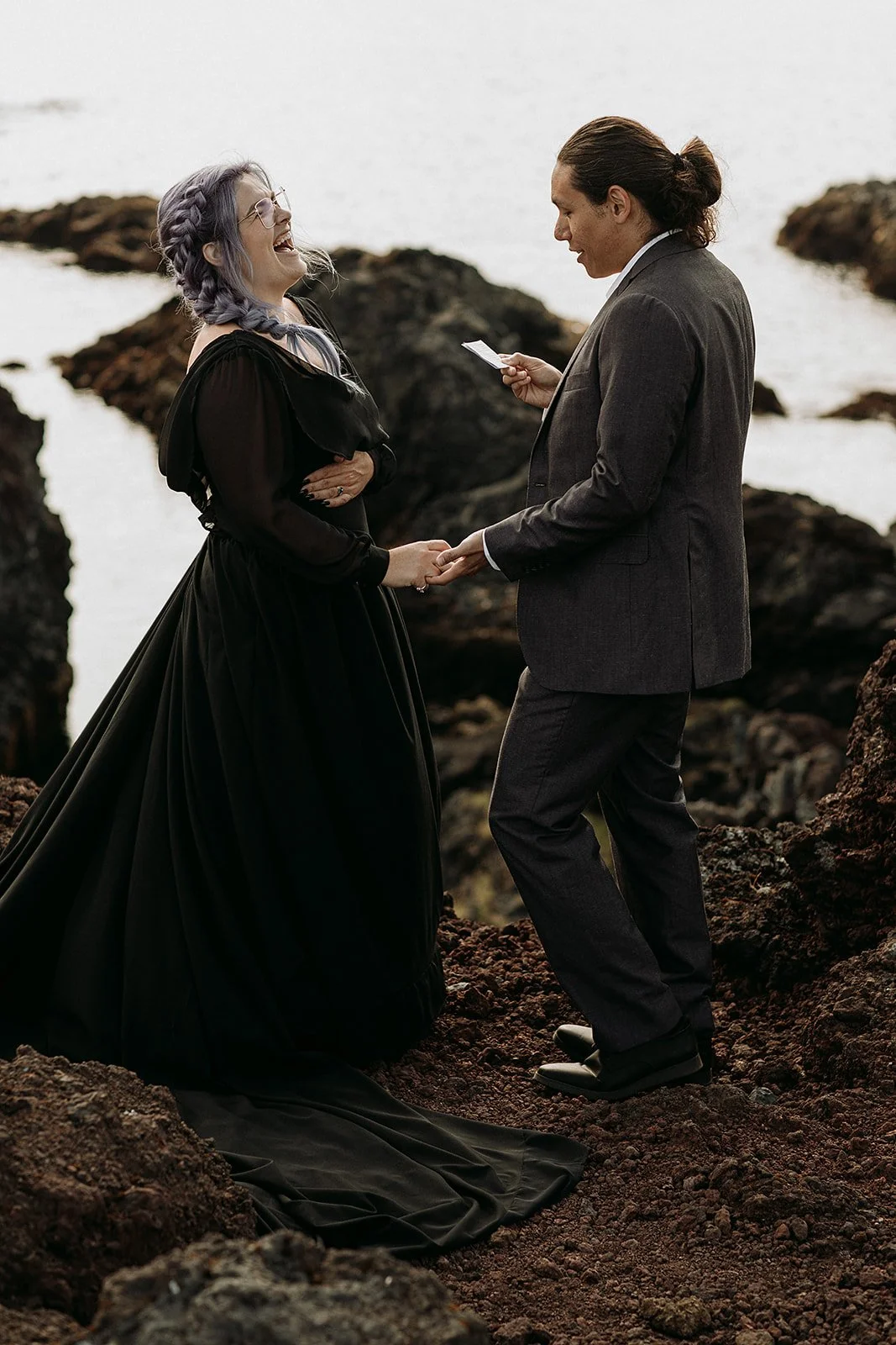 private Iceland elopement with the couple laughing during their vows and bride in black wedding dress.