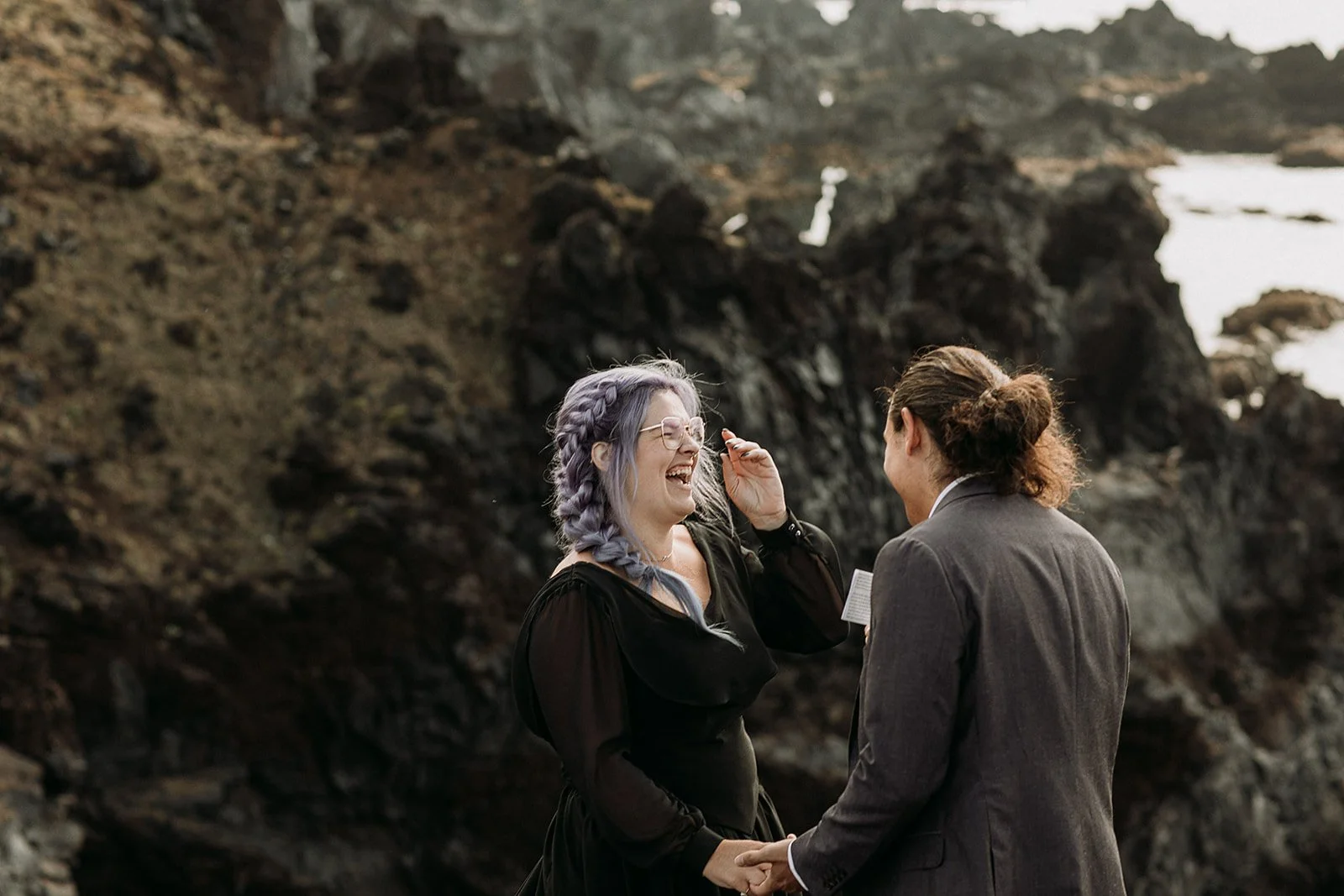 Alternative Iceland elopement couple wearing black wedding dress and purple hair — couple saying vows wedding ceremony
