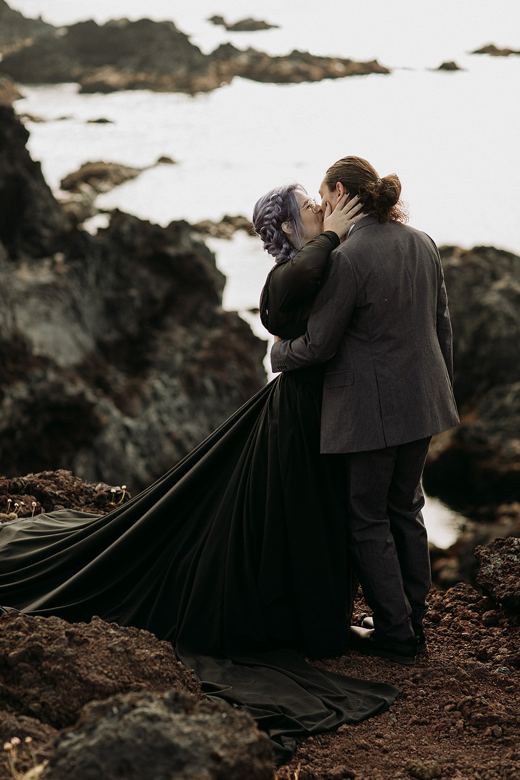 Alternative Iceland elopement couple wearing black wedding dress and purple hair — couple saying vows wedding ceremony