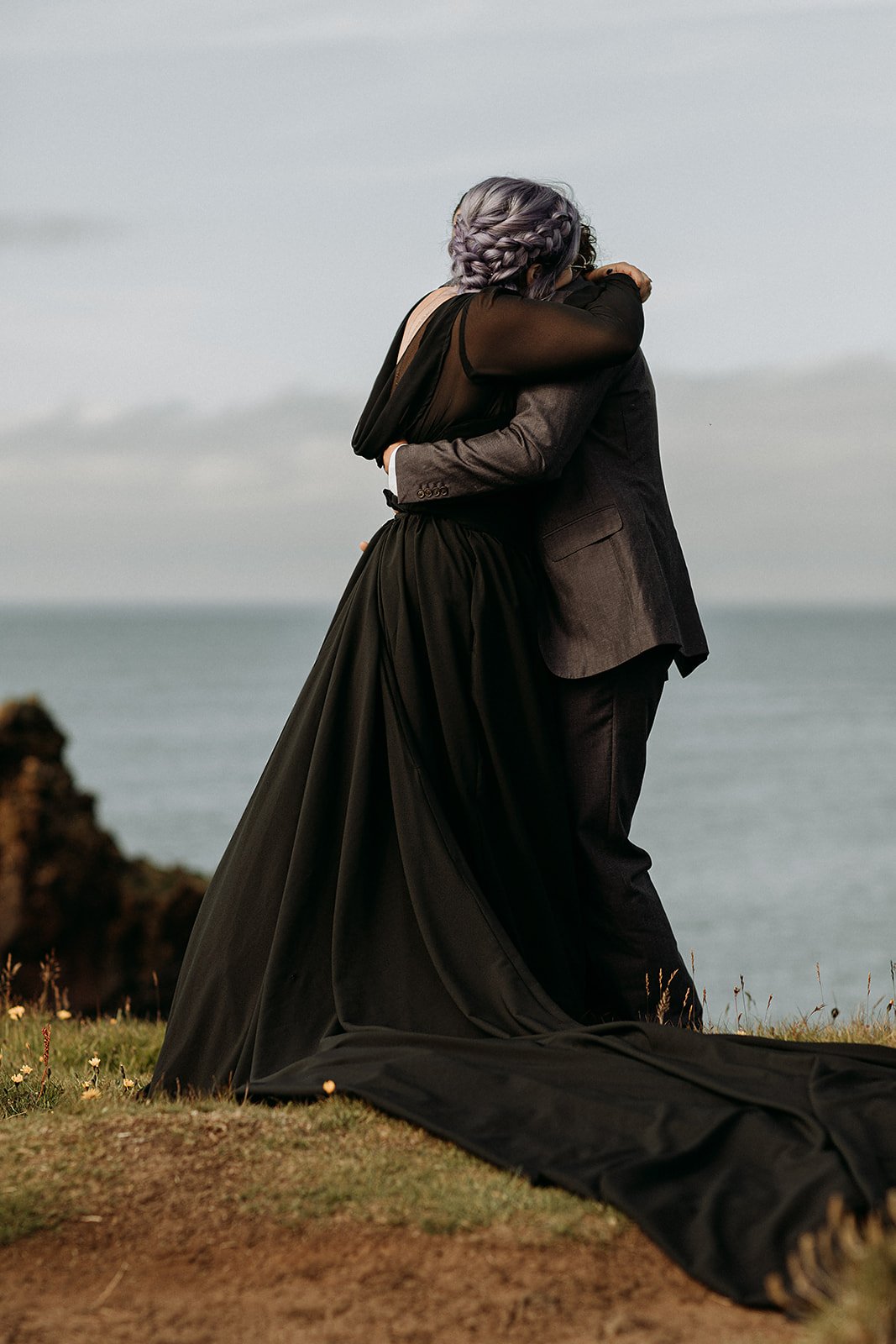 Alternative Iceland elopement couple wearing black wedding dress and purple hair — couple saying vows wedding ceremony