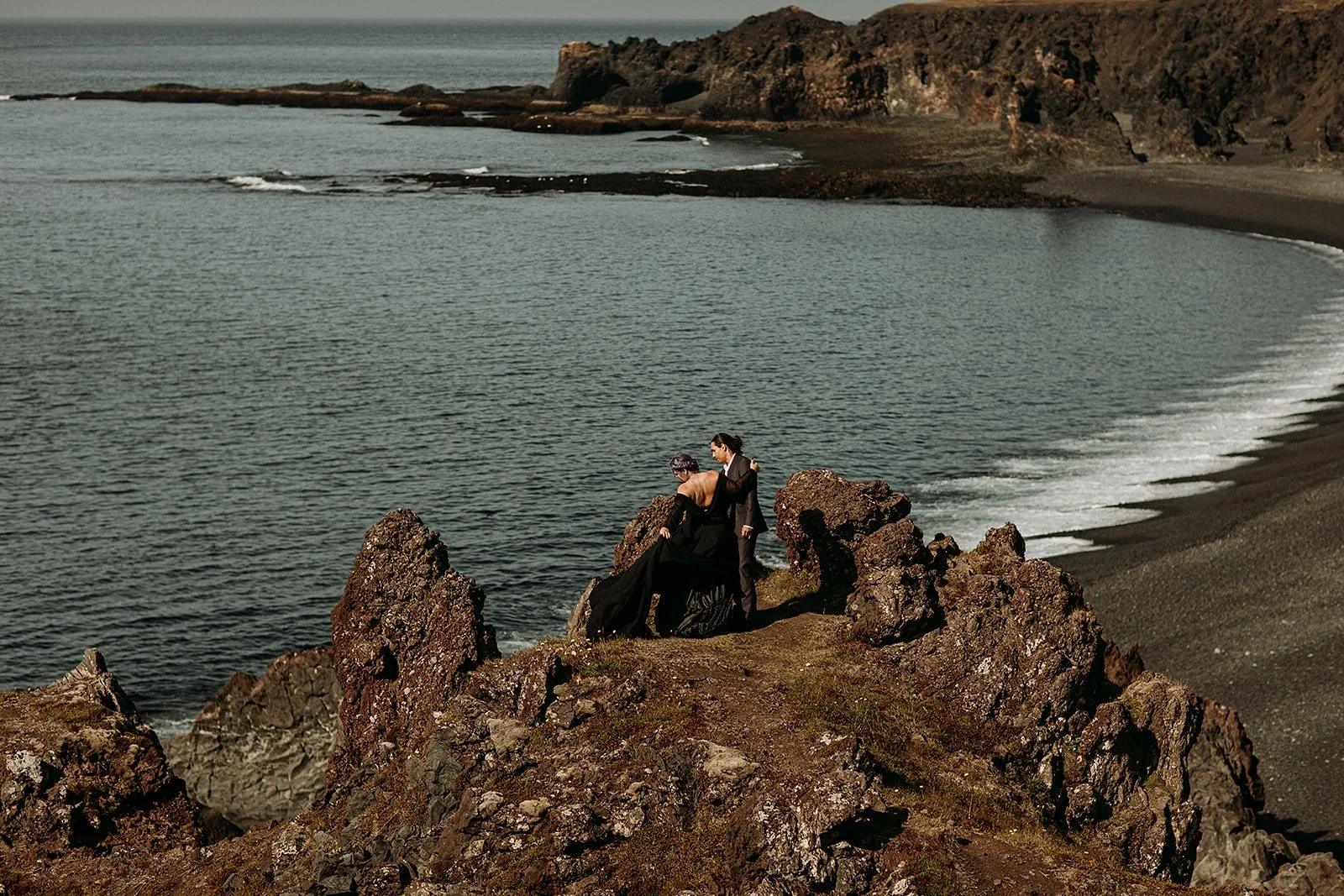 Alternative Iceland elopement couple wearing black wedding dress and purple hair — couple portraits black sand beach