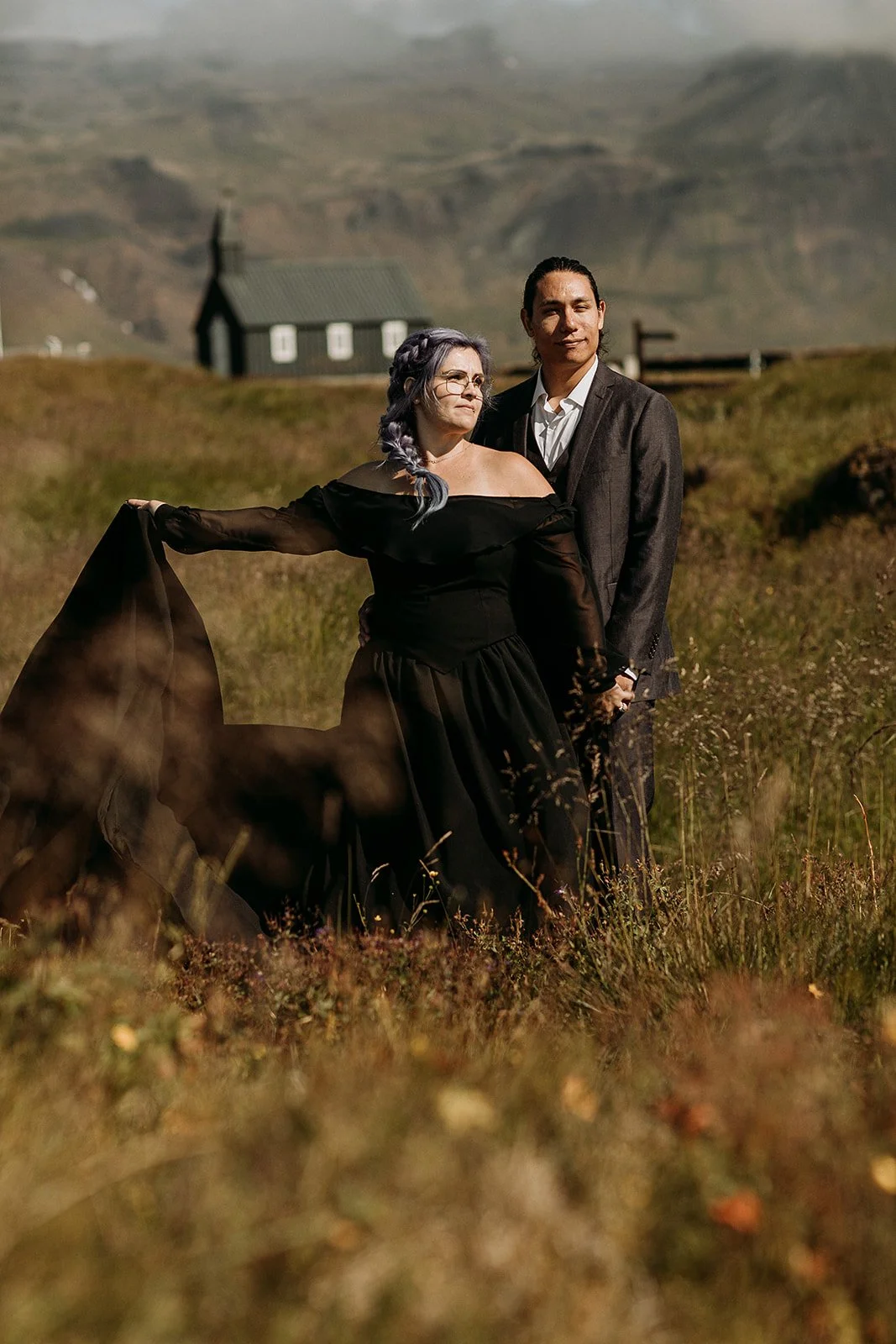 Alternative Iceland elopement couple wearing black wedding dress and purple hair — couple portraits at black church