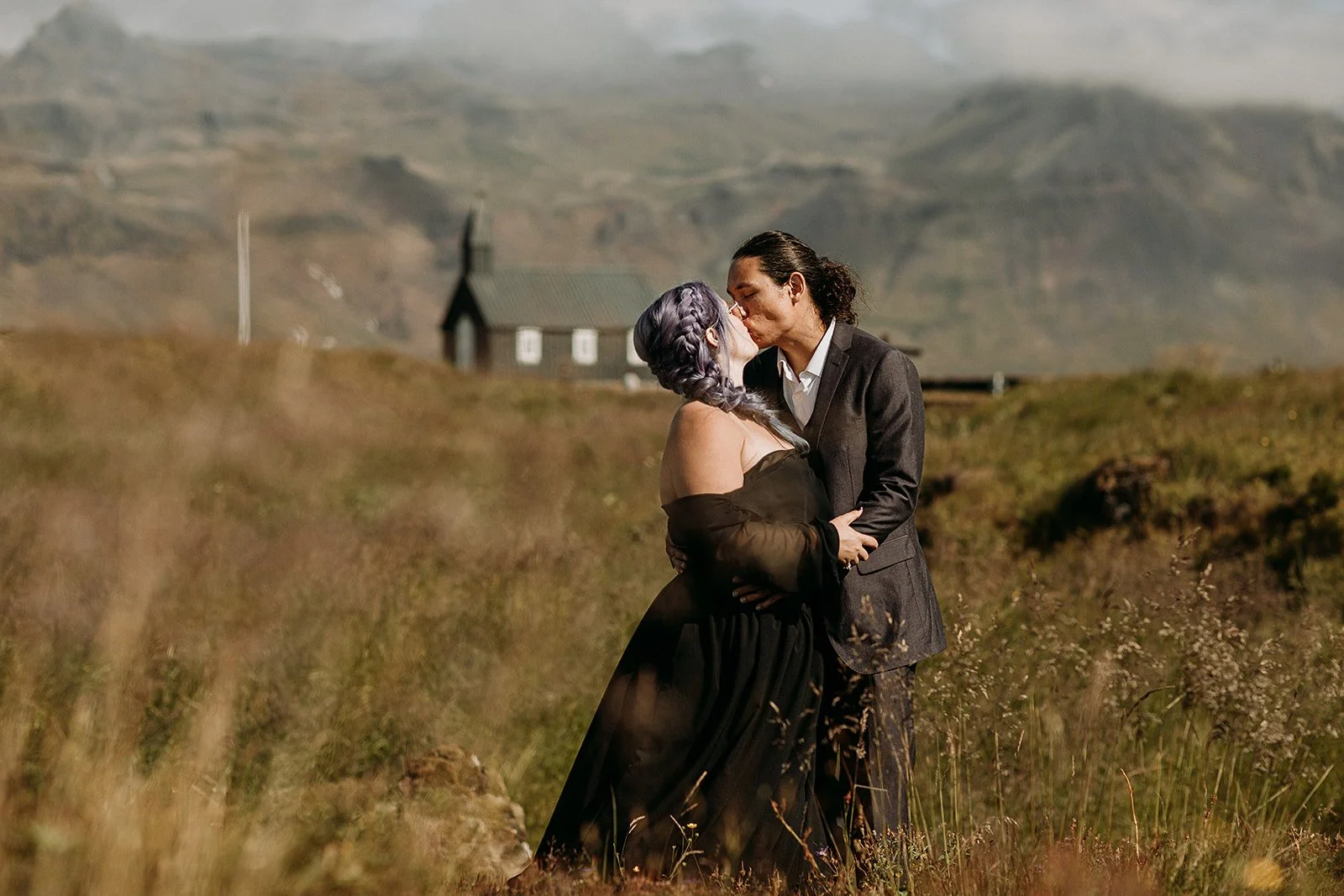 Alternative Iceland elopement couple wearing black wedding dress and purple hair — couple portraits at black church