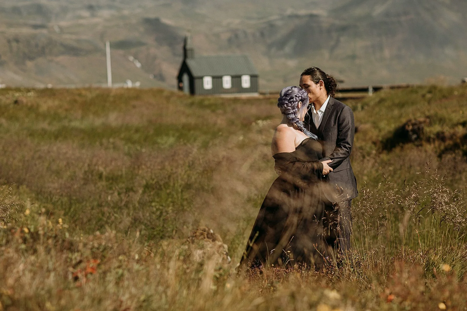 Alternative Iceland elopement couple wearing black wedding dress and purple hair — couple portraits at black church