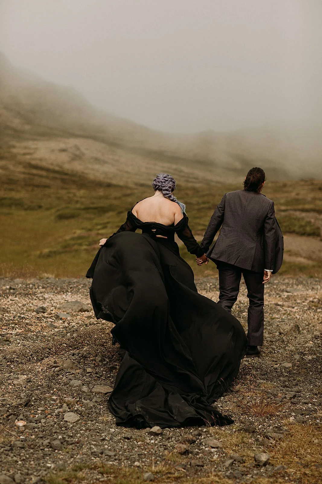 Alternative Iceland elopement couple wearing black wedding dress and purple hair — couple portraits at mountain