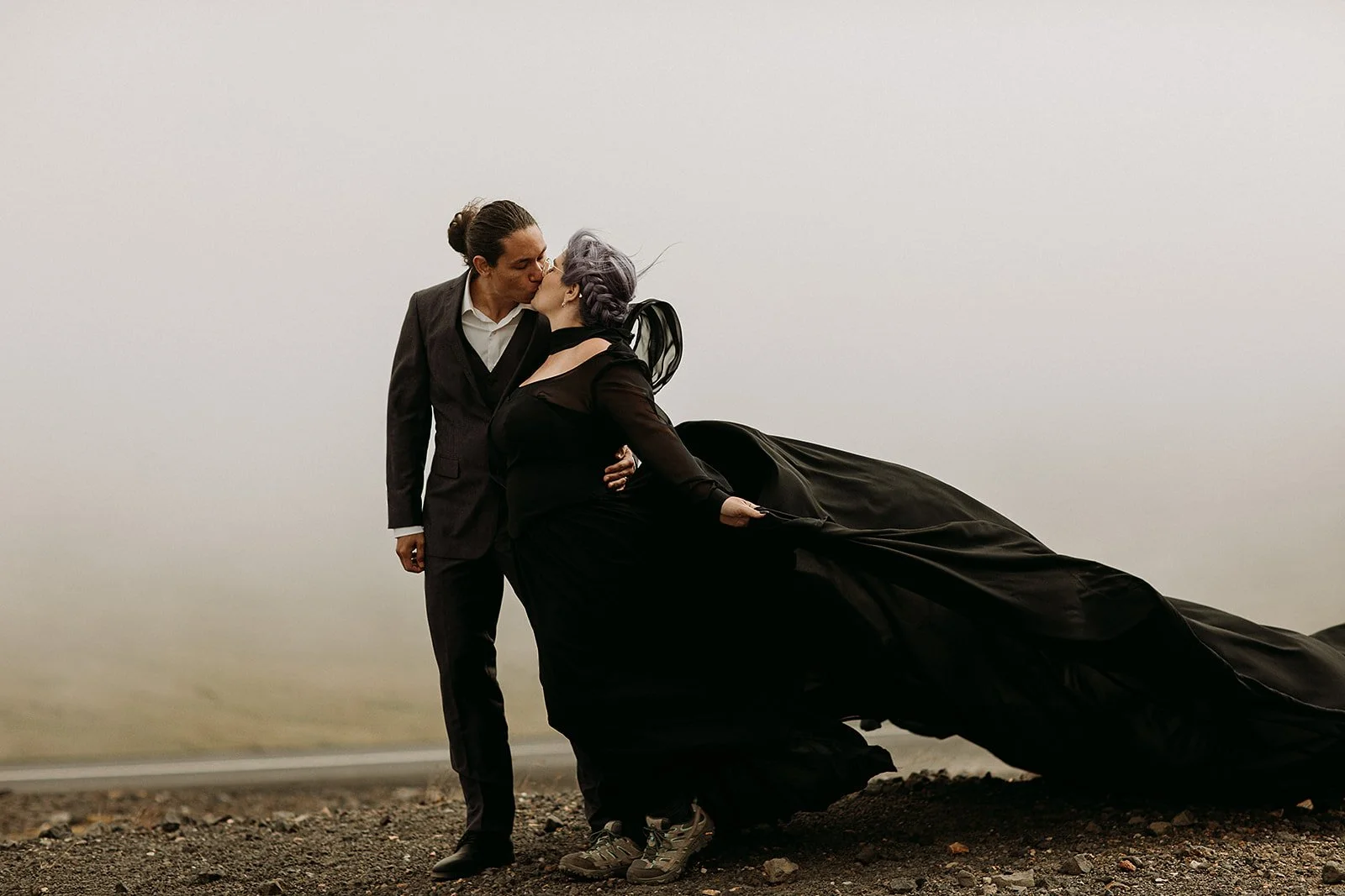 Alternative Iceland elopement couple wearing black wedding dress and purple hair — couple portraits at mountain