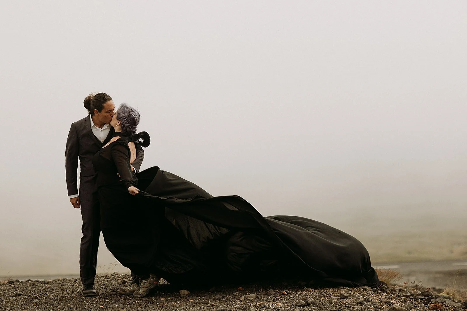 Alternative Iceland elopement couple wearing black wedding dress and purple hair — couple portraits at mountain