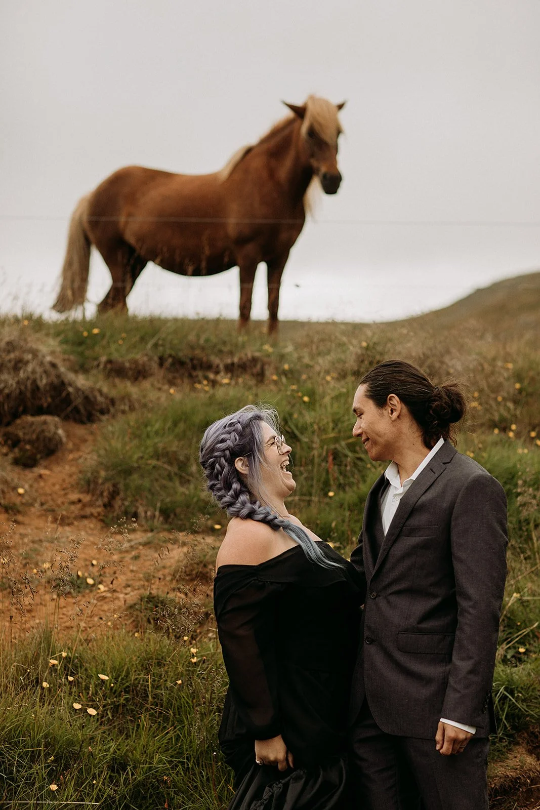 Alternative Iceland elopement couple wearing black wedding dress and purple hair — couple portraits with Icelandic horse