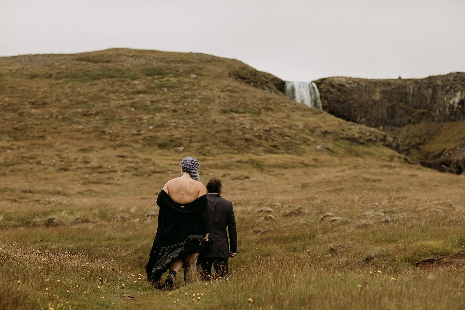 Alternative Iceland elopement couple wearing black wedding dress and purple hair — couple portraits at mountain