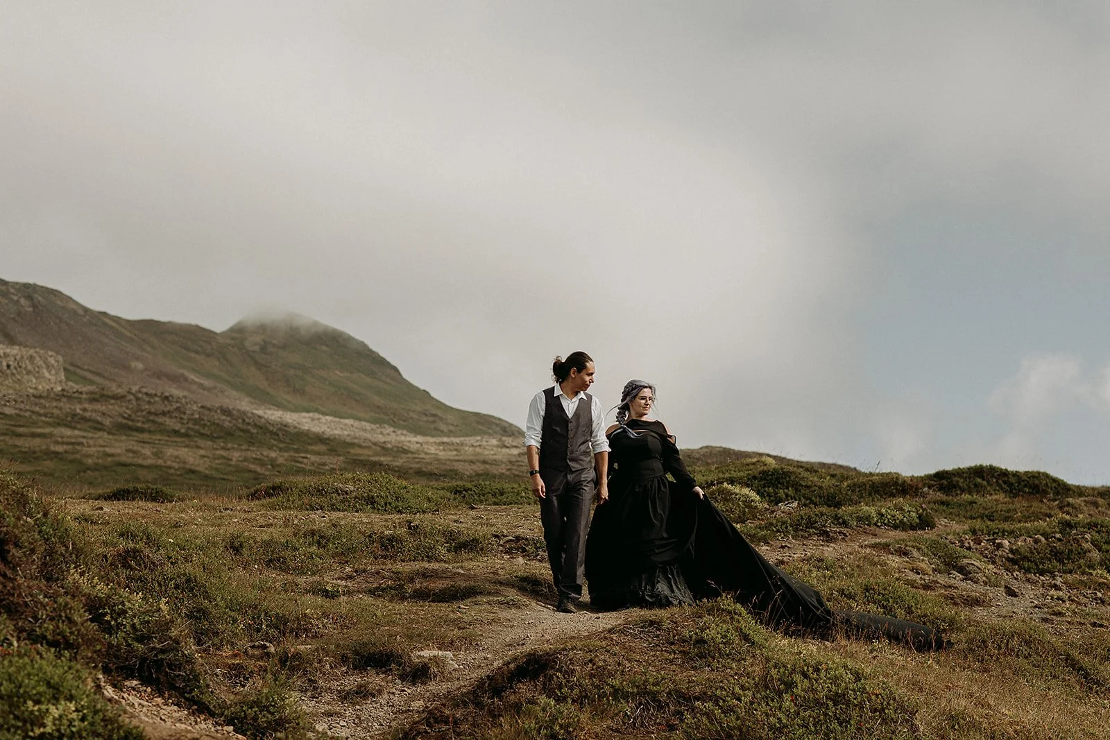 Alternative Iceland elopement couple wearing black wedding dress and purple hair — couple portraits at volcanic area