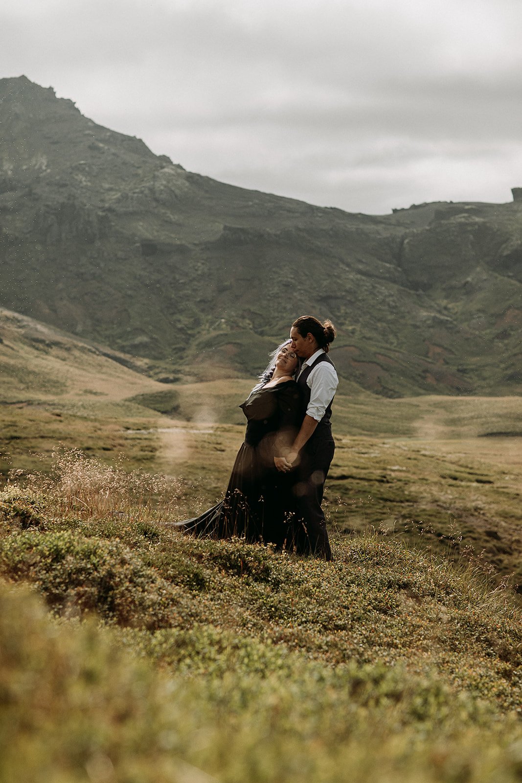 Alternative Iceland elopement couple wearing black wedding dress and purple hair — couple portraits at beach