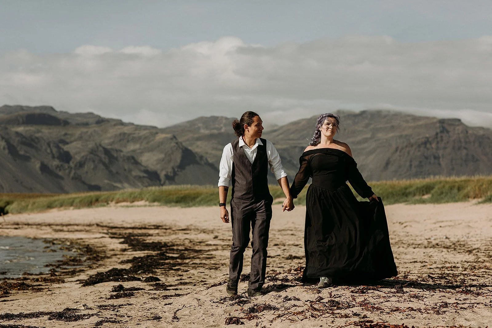 Alternative Iceland elopement couple wearing black wedding dress and purple hair — couple portraits at beach