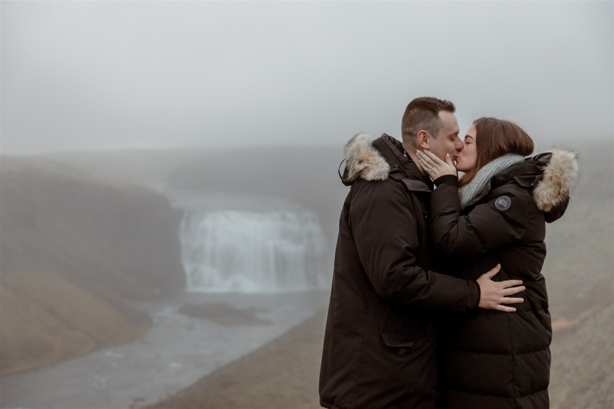  Secret Iceland Proposal at a Foggy Winter Waterfall by a local Iceland Engagement &amp; Proposal Photographer and planner —couple hugs 