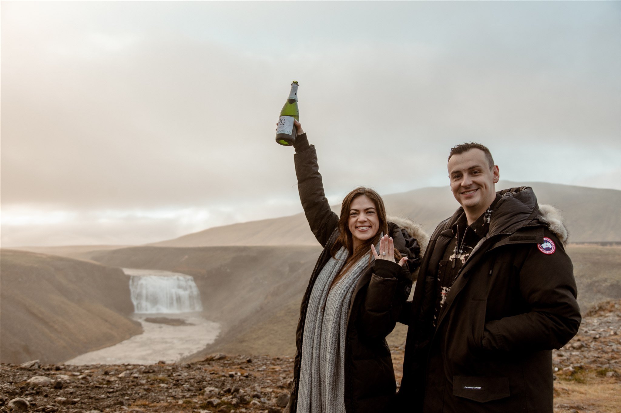 Iceland proposal in the autumn at a private waterfall with the couple drinking champagne after the proposal