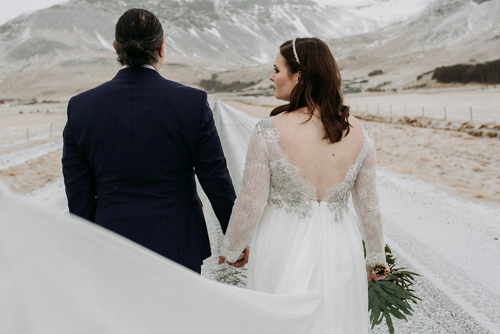 A Winter Iceland Elopement at Skógafoss (Skogafoss) and Glacier — couple in front of mountains walking down road