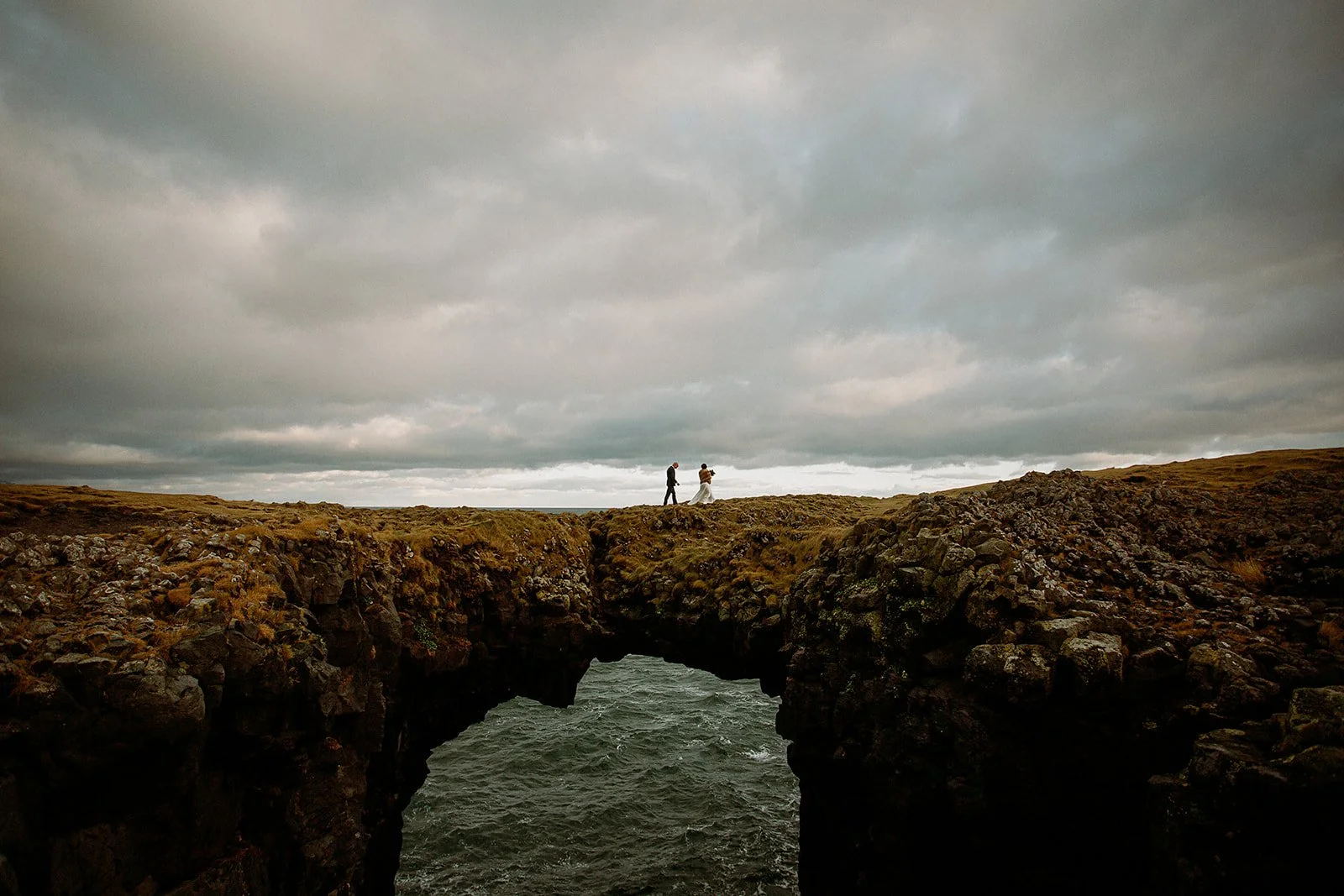 A Private Multi-Area Iceland Elopement by Steph Zakas Photography with wedding couple at sea cliff rock arch