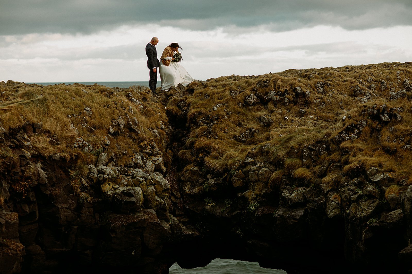A Private Multi-Area Iceland Elopement by Steph Zakas Photography with wedding couple at sea cliff rock arch