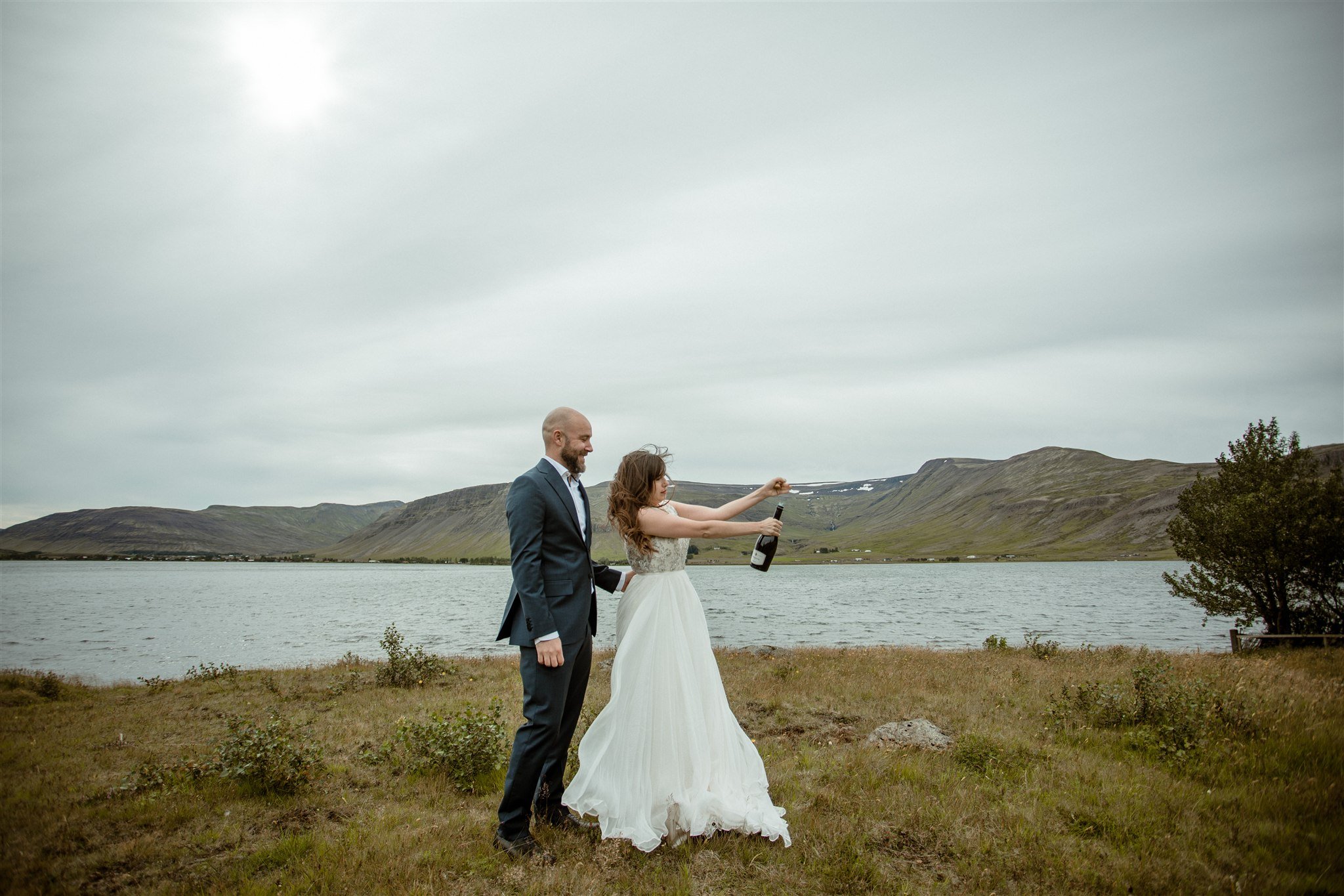  A Private Lake Iceland Elopement Starting in Reykjavík with Guests — couple after ceremony popping champagne 
