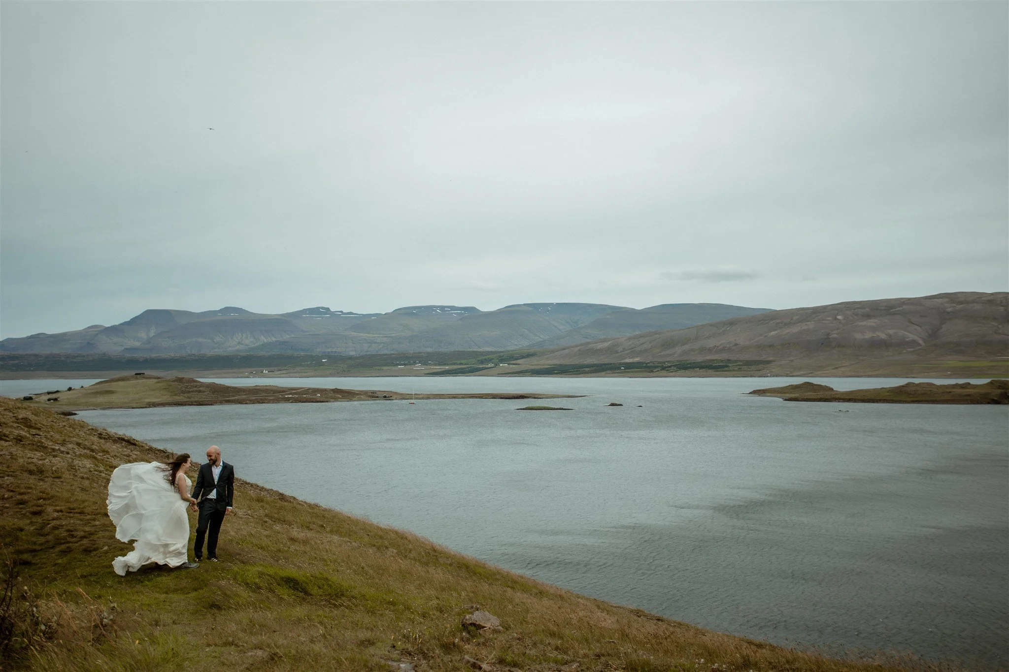  A Private Lake Iceland Elopement Starting in Reykjavík with Guests by Iceland elopement photographer &amp; planner Steph Zakas — couple on an adventure for elopement photos at a fjord in the wind 