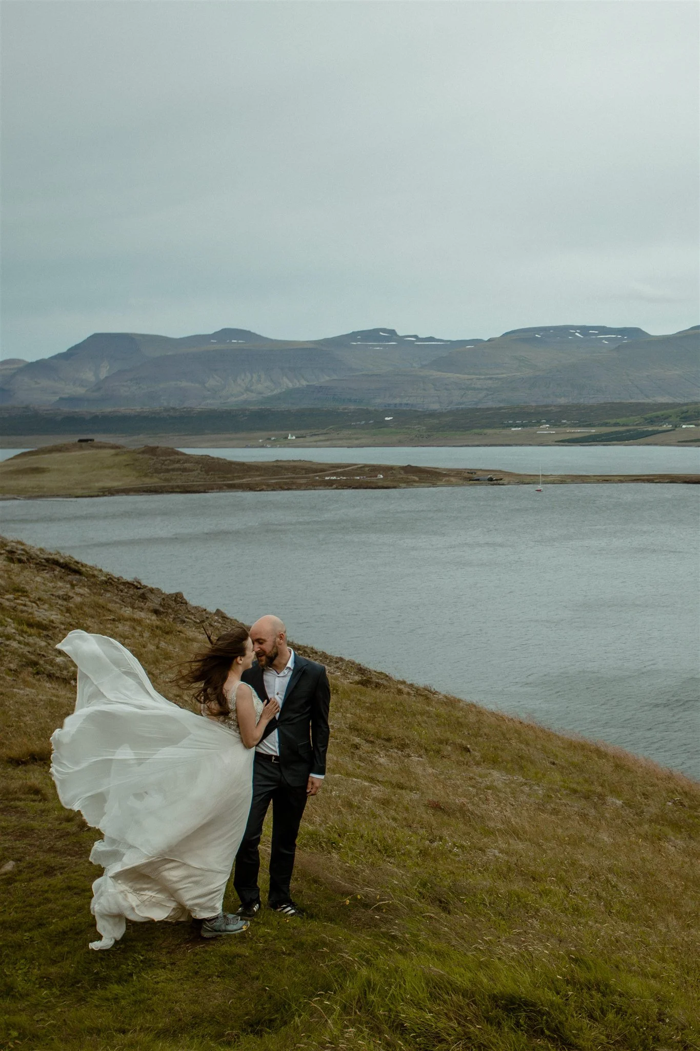  A Private Lake Iceland Elopement Starting in Reykjavík with Guests by Iceland elopement photographer &amp; planner Steph Zakas — couple on an adventure for elopement photos at a fjord in the wind 