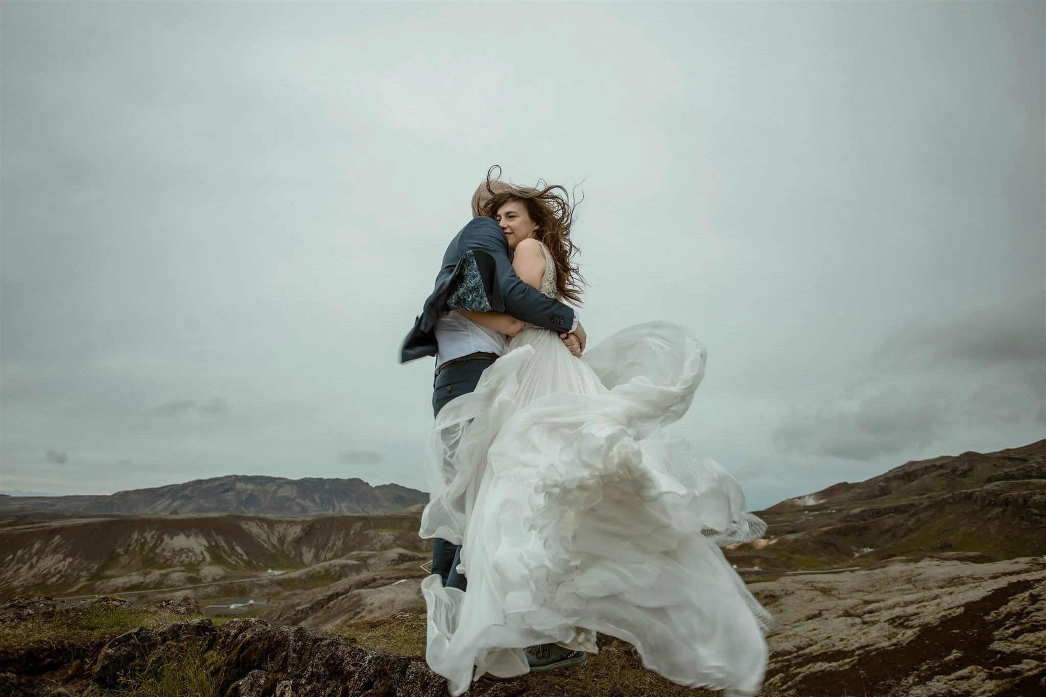  A Private Lake Iceland Elopement Starting in Reykjavík with Guests by Iceland elopement photographer &amp; planner Steph Zakas — couple on an adventure for elopement photos at a volcanic area with wind 