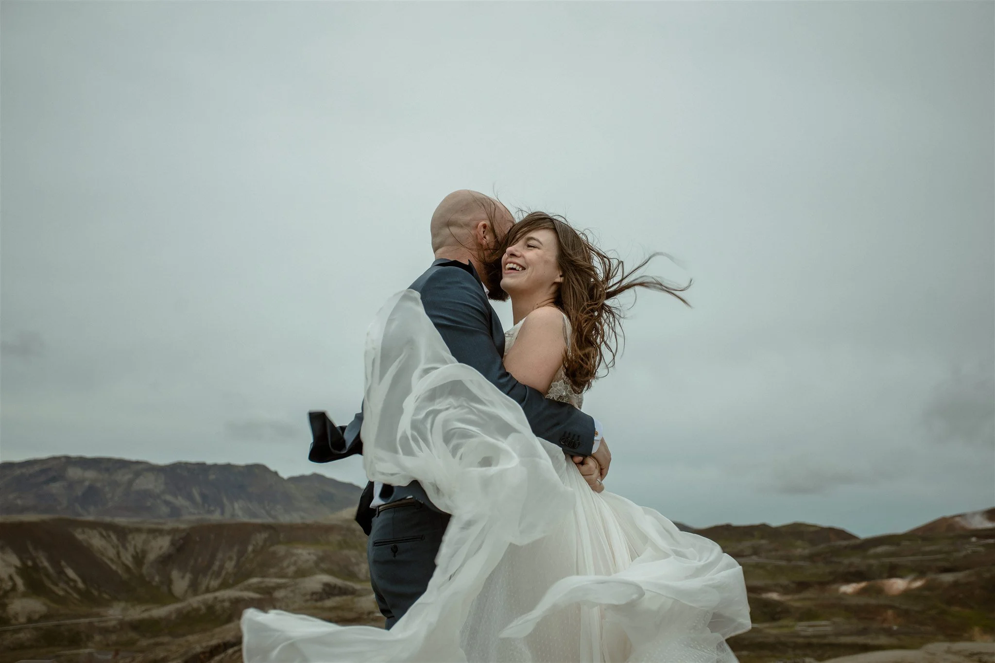  A Private Lake Iceland Elopement Starting in Reykjavík with Guests by Iceland elopement photographer &amp; planner Steph Zakas — couple on an adventure for elopement photos at a volcanic area with wind 