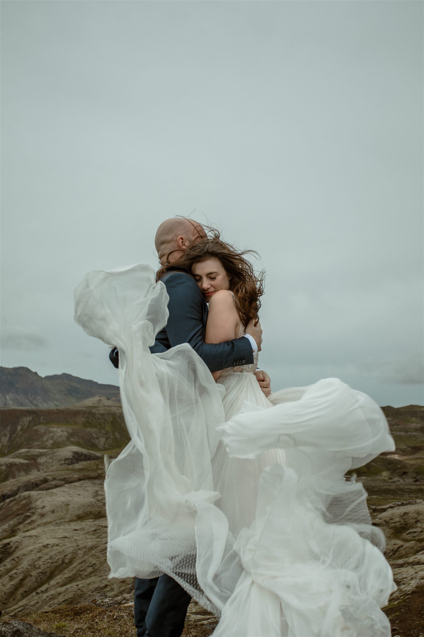  A Private Lake Iceland Elopement Starting in Reykjavík with Guests by Iceland elopement photographer &amp; planner Steph Zakas — couple on an adventure for elopement photos at a volcanic area with wind 
