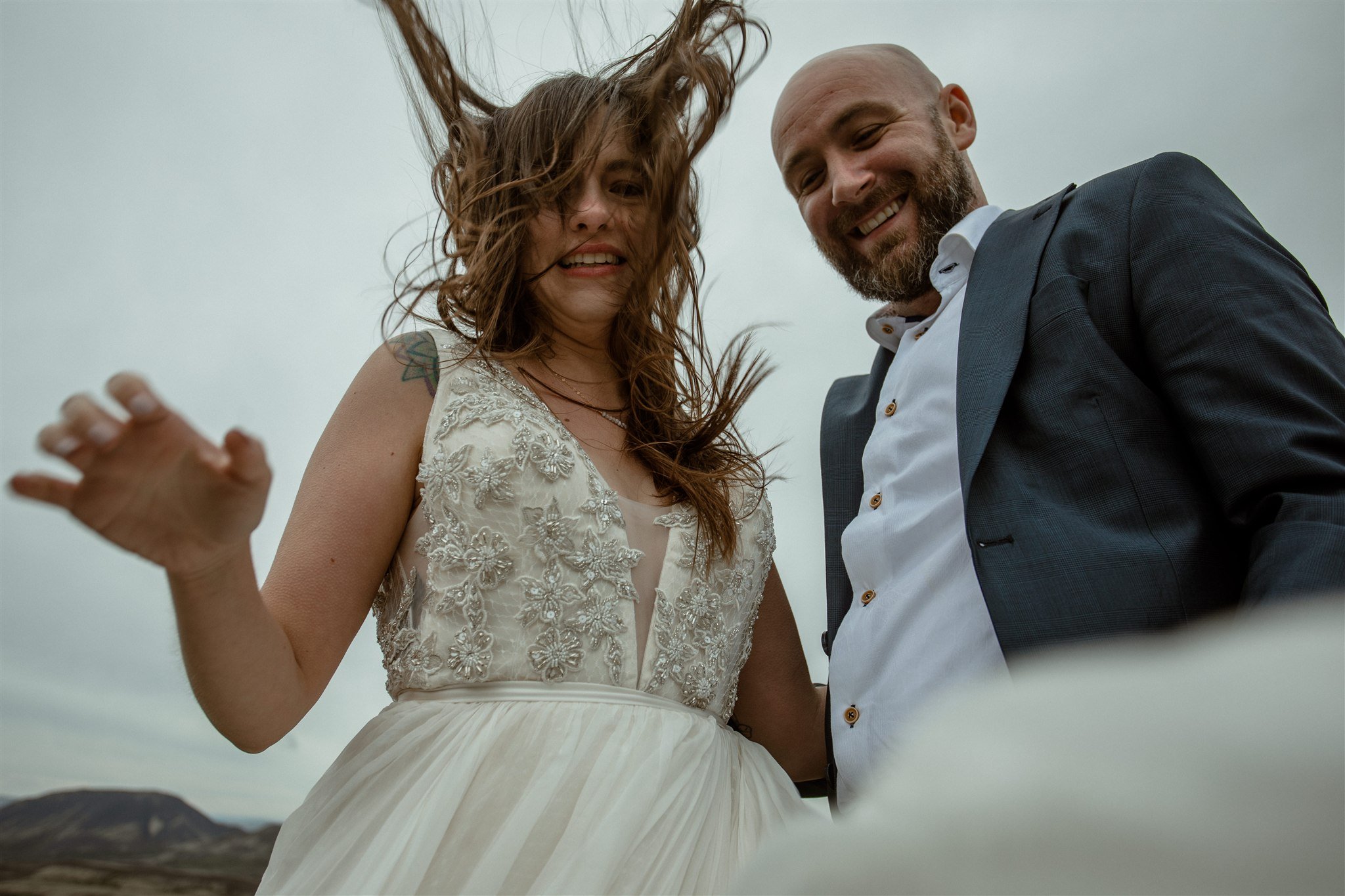  A Private Lake Iceland Elopement Starting in Reykjavík with Guests by Iceland elopement photographer &amp; planner Steph Zakas — couple on an adventure for elopement photos at a volcanic area with wind 
