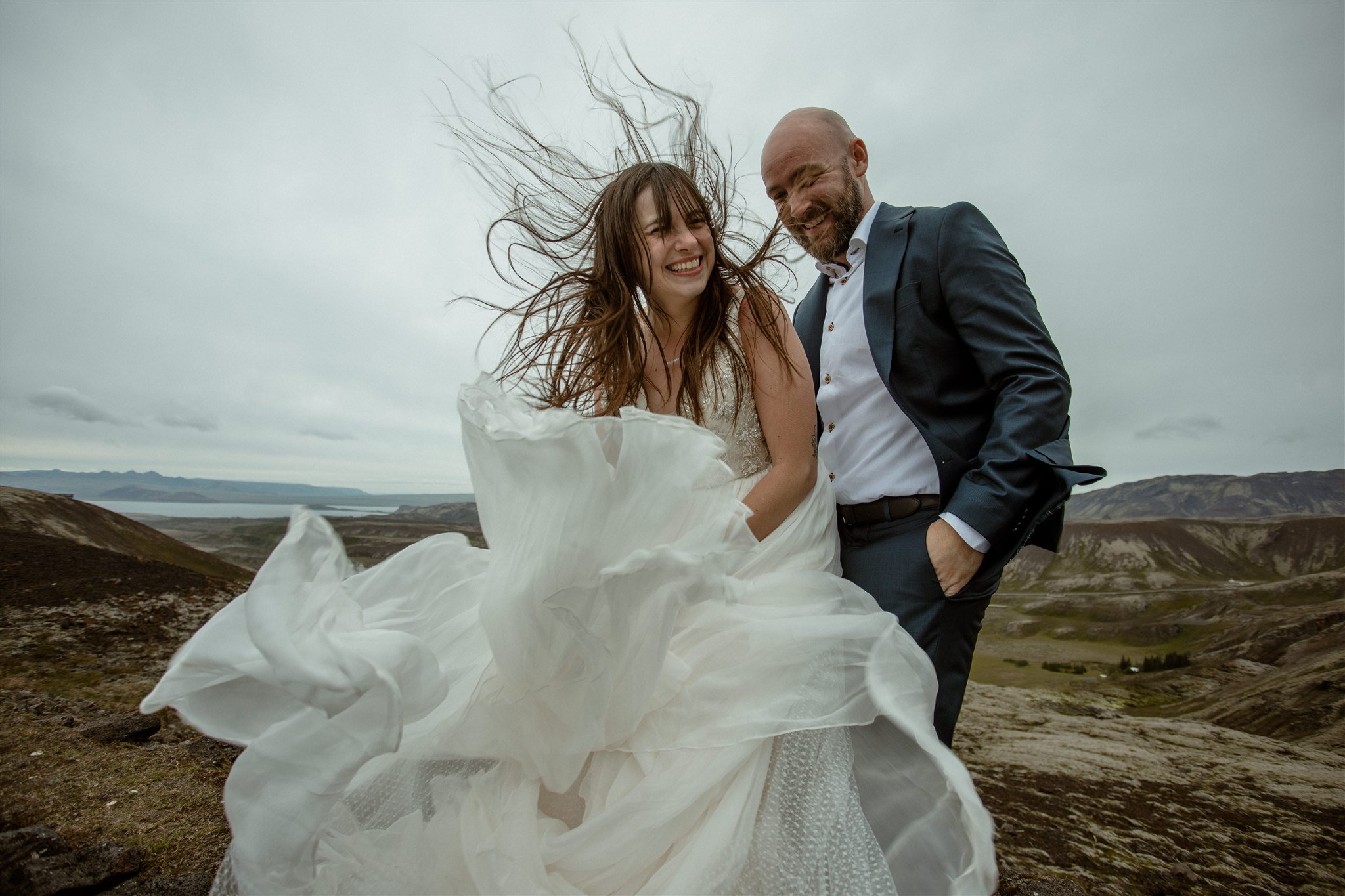 A Private Lake Iceland Elopement Starting in Reykjavík with Guests by Iceland elopement photographer &amp; planner Steph Zakas — couple on an adventure for elopement photos at a volcanic area with wind 