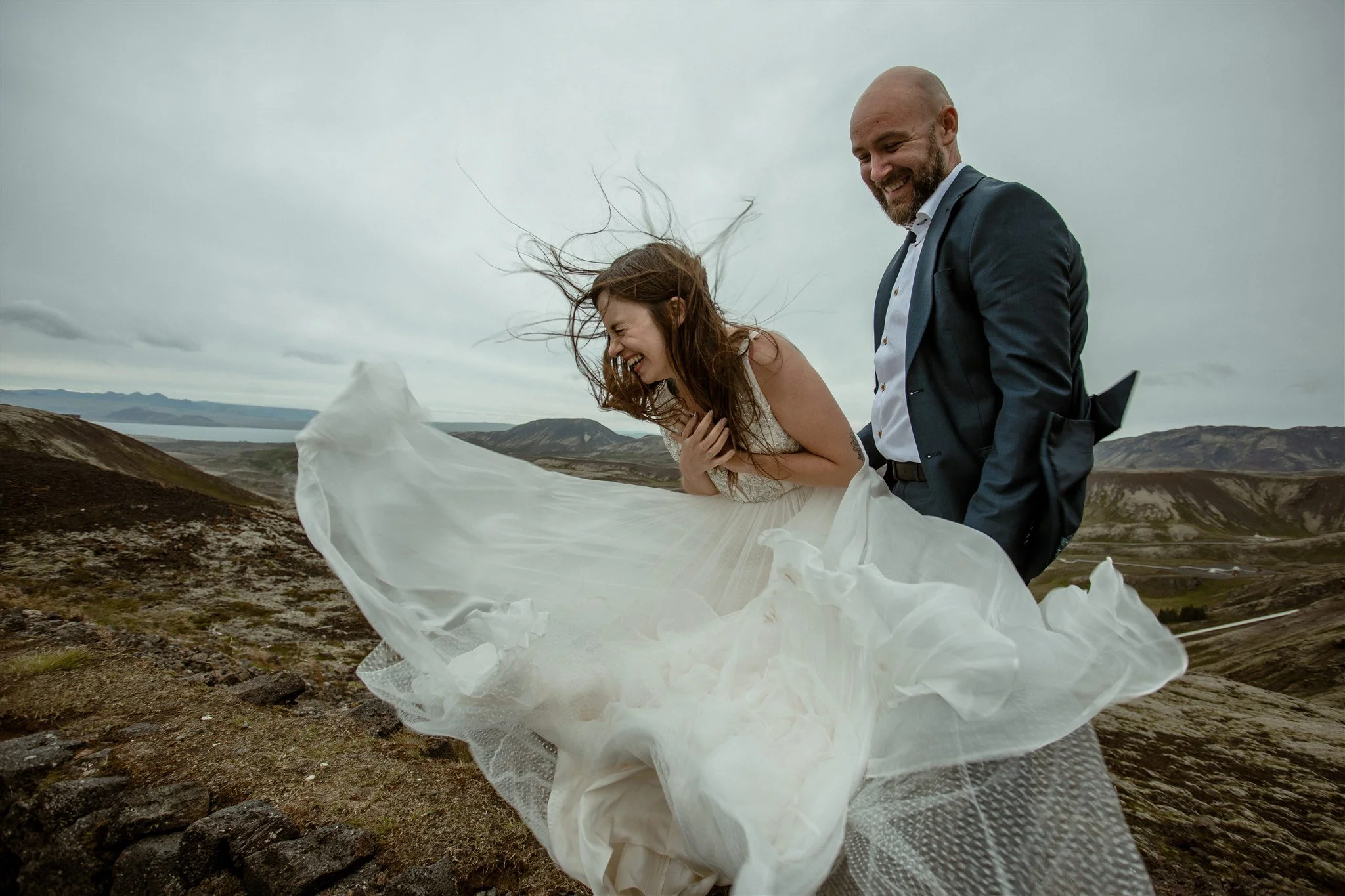  A Private Lake Iceland Elopement Starting in Reykjavík with Guests by Iceland elopement photographer &amp; planner Steph Zakas — couple on an adventure for elopement photos at a volcanic area with wind 