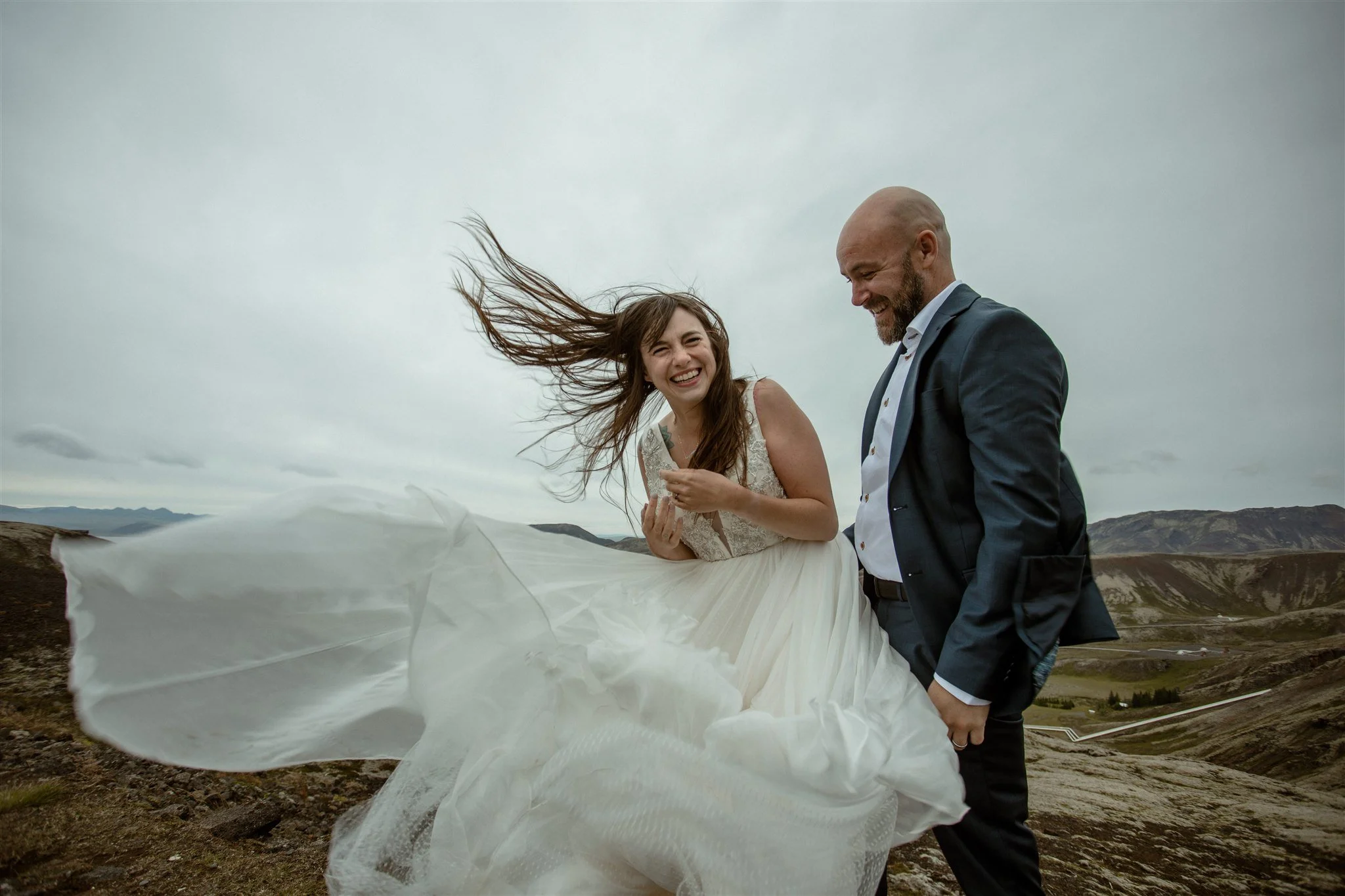  A Private Lake Iceland Elopement Starting in Reykjavík with Guests by Iceland elopement photographer &amp; planner Steph Zakas — couple on an adventure for elopement photos at a volcanic area with wind 