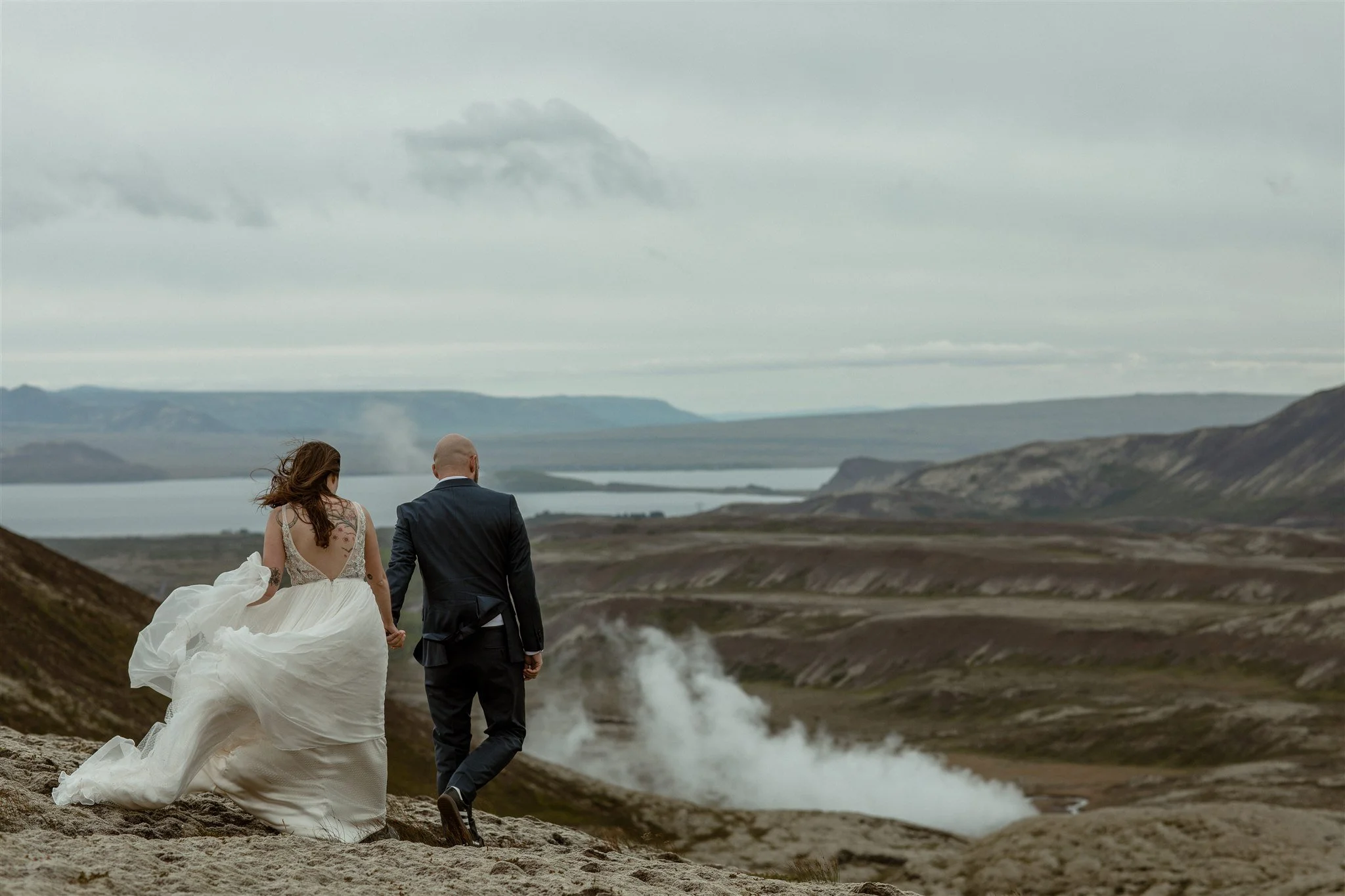  A Private Lake Iceland Elopement Starting in Reykjavík with Guests by Iceland elopement photographer &amp; planner Steph Zakas — couple on an adventure for elopement photos at a volcanic area with wind 