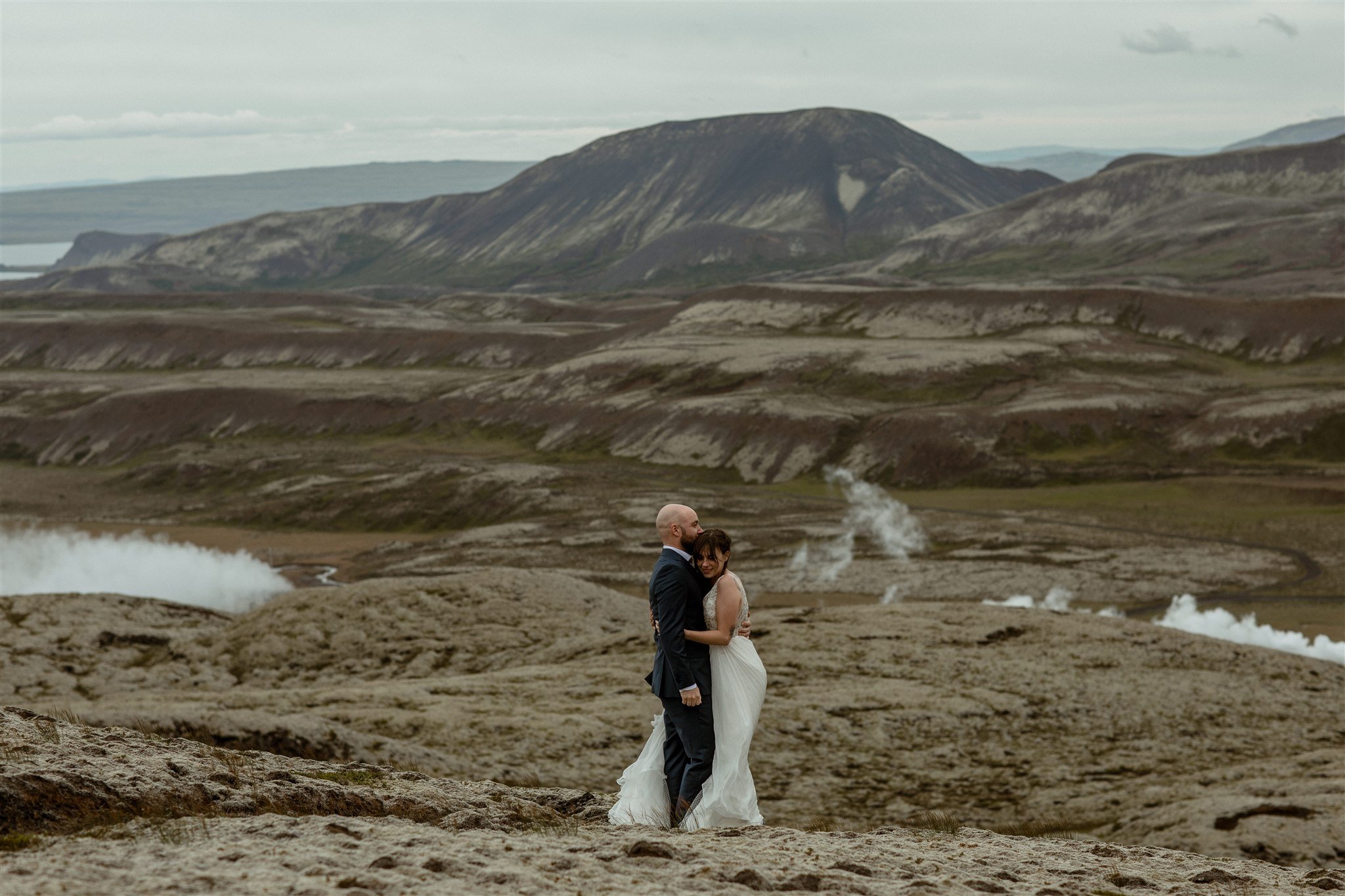  A Private Lake Iceland Elopement Starting in Reykjavík with Guests by Iceland elopement photographer &amp; planner Steph Zakas — couple on an adventure for elopement photos at a volcanic area with wind 