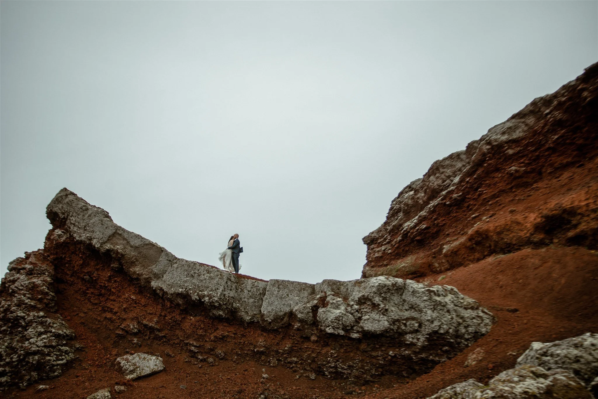  A Private Lake Iceland Elopement Starting in Reykjavík with Guests by Iceland elopement photographer &amp; planner Steph Zakas — couple on an adventure for elopement photos at a volcanic red area  