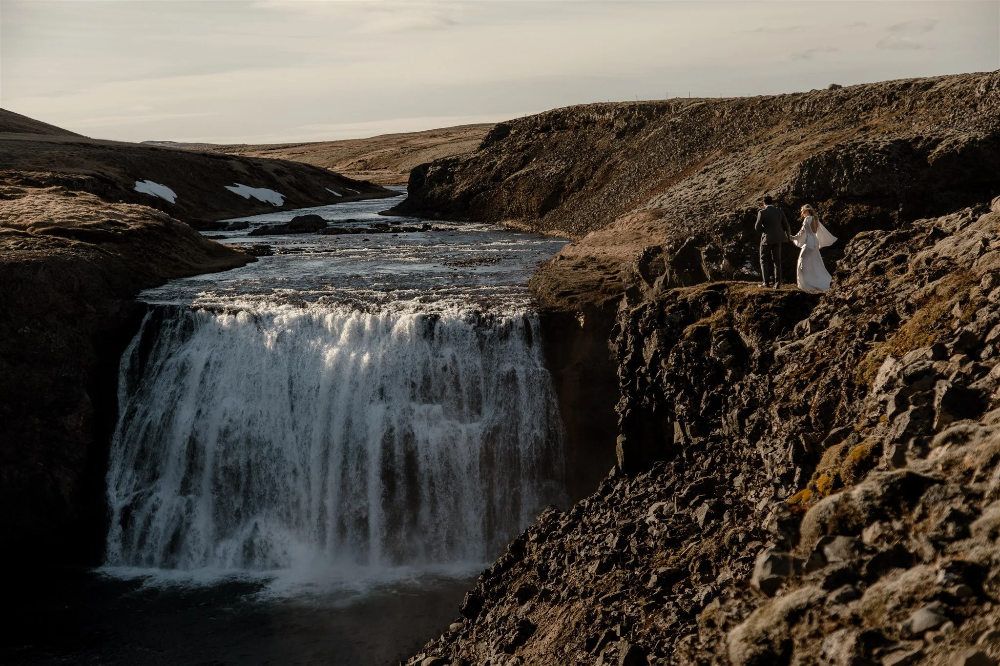 Lord of the Rings Inspired Iceland Engagement Photoshoot at waterfall — couple walking by mountains