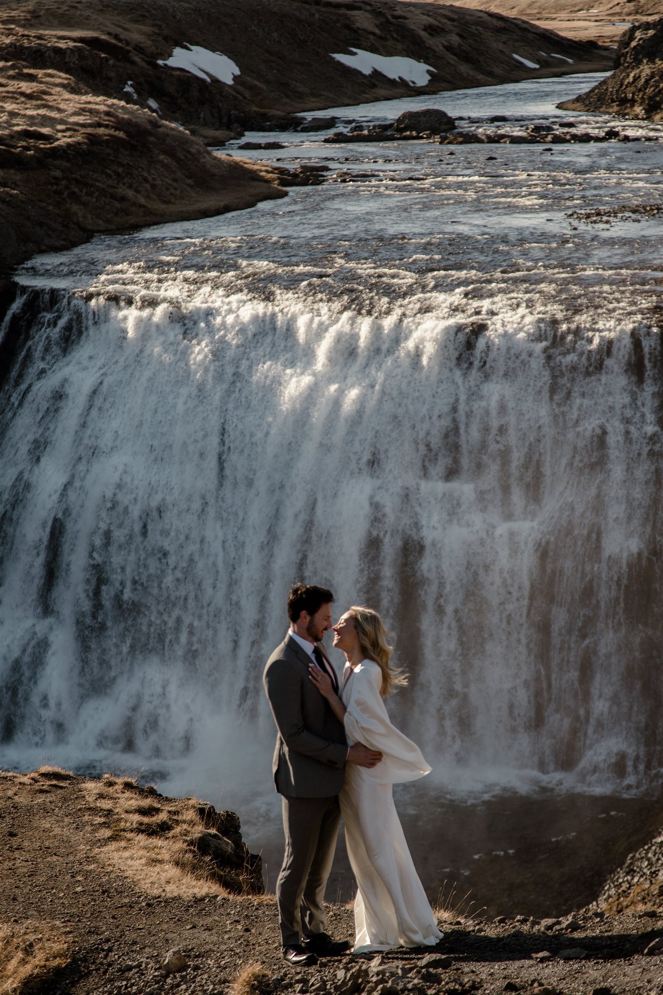 Lord of the Rings Inspired Iceland Engagement Photoshoot at waterfall — couple holding each other with Arwen inspired dress