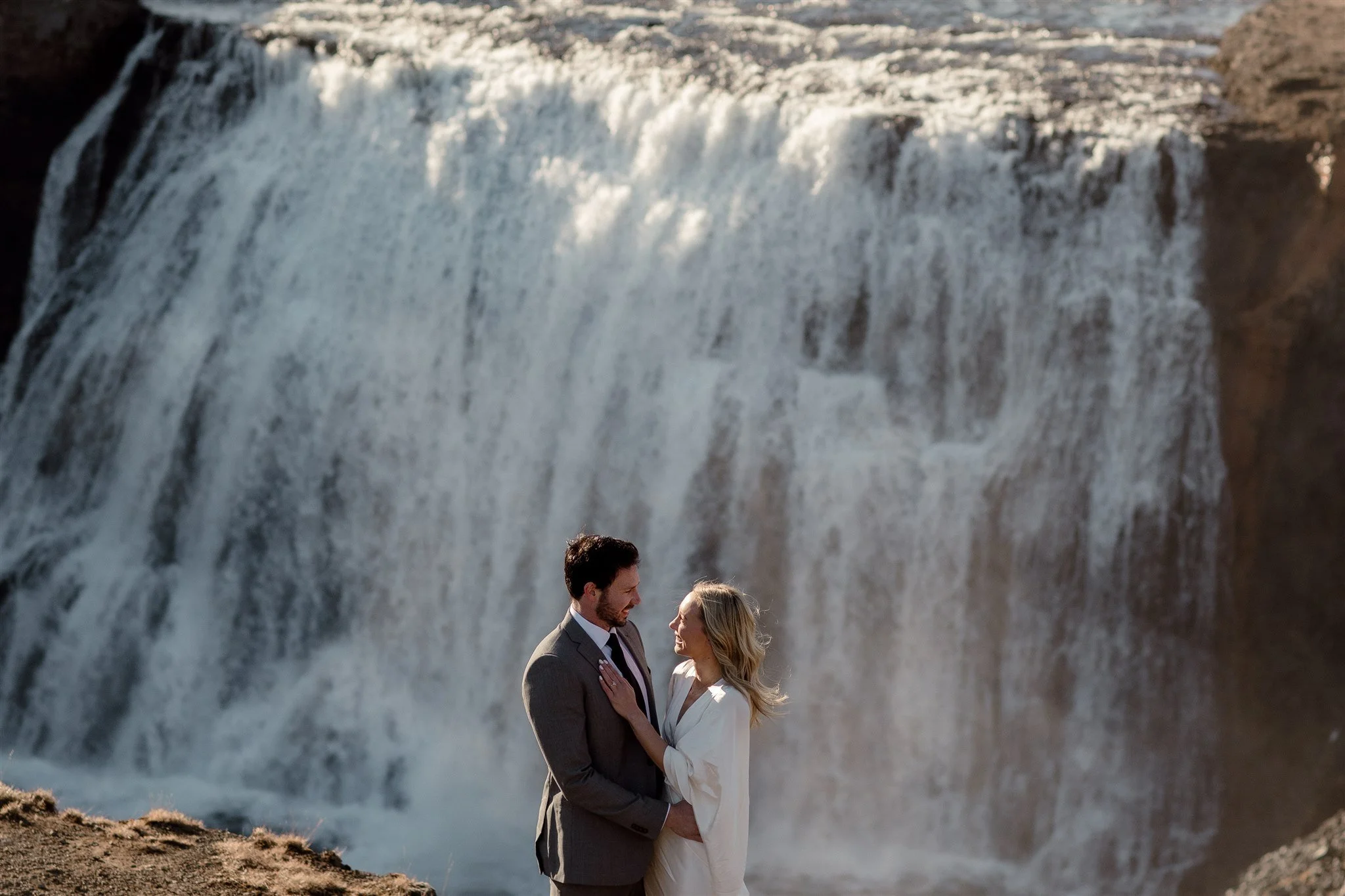 Lord of the Rings Inspired Iceland Engagement Photoshoot at waterfall — couple walking with Arwen inspired dress