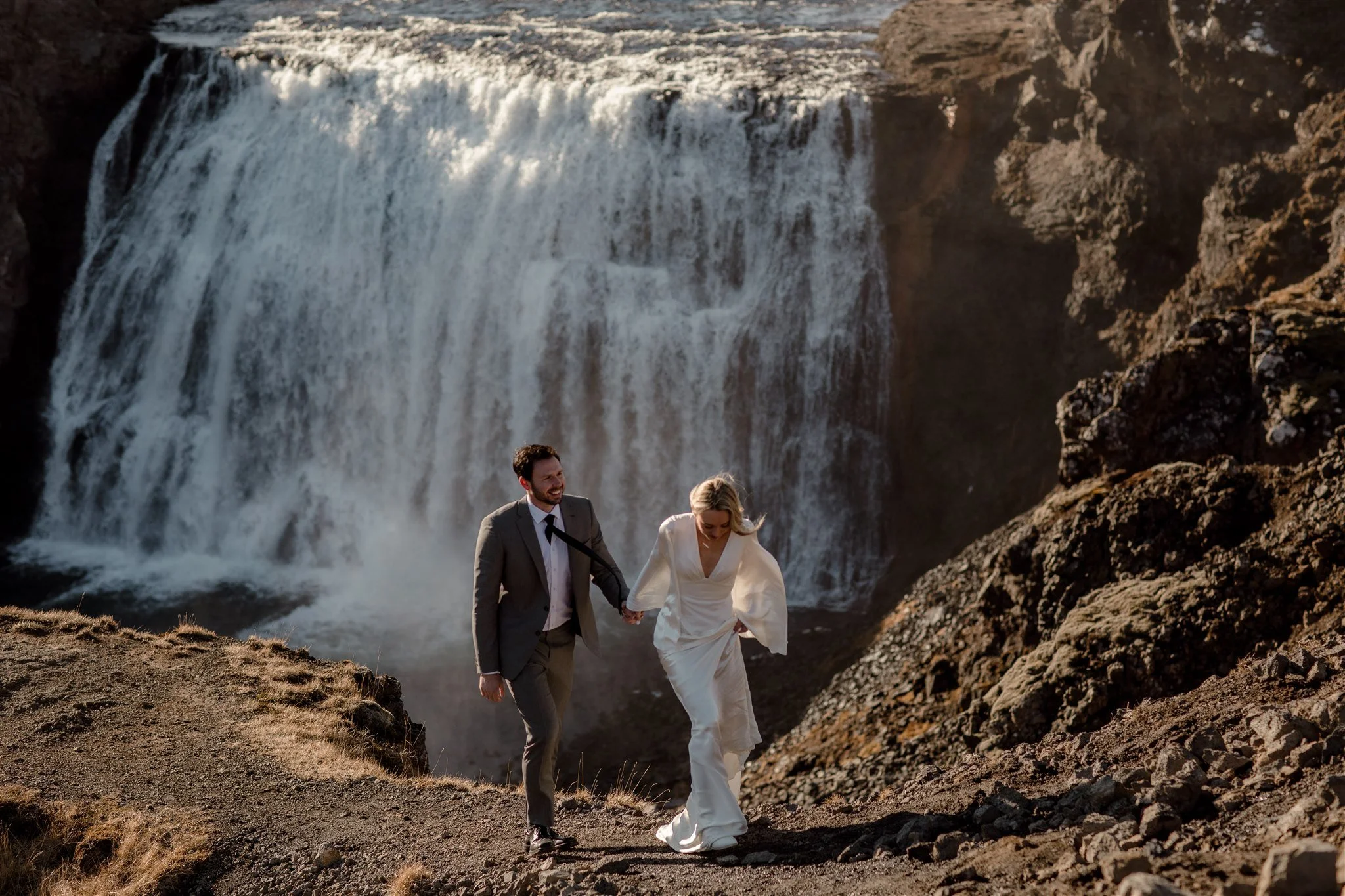Lord of the Rings Inspired Iceland Engagement Photoshoot at waterfall — couple walking with Arwen inspired dress