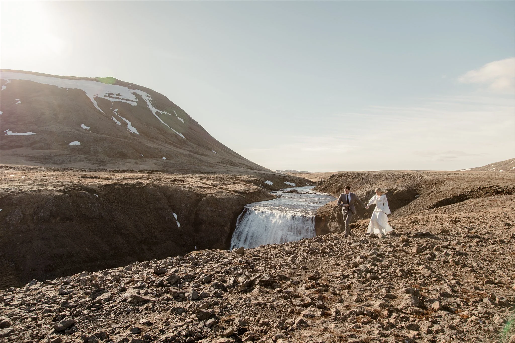 Lord of the Rings Inspired Iceland Engagement Photoshoot at waterfall — couple walking with Arwen inspired dress