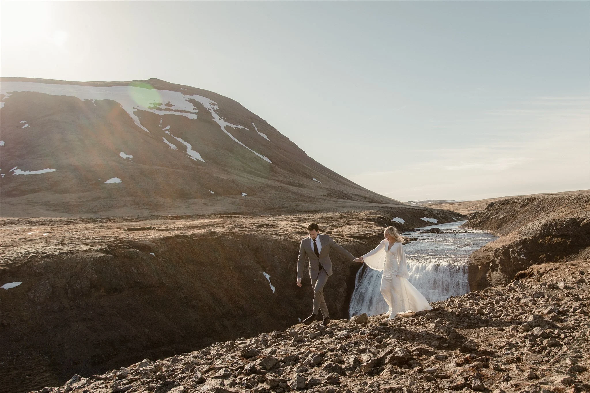 Lord of the Rings Inspired Iceland Engagement Photoshoot at waterfall — couple walking with Arwen inspired dress